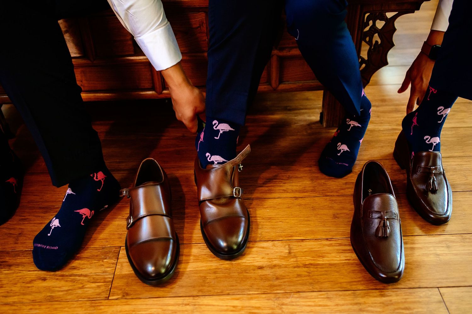 A row of dress shoes and formal footwear lined up on a hardwood floor showing different styles and angles.