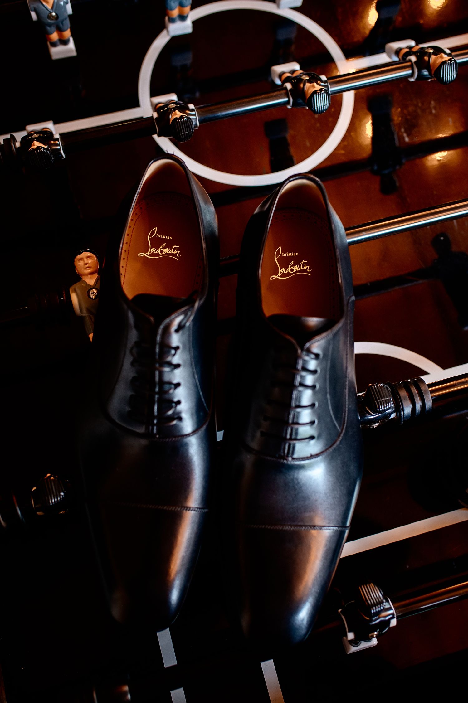 Black leather formal shoes displayed on wooden shoe racks with warm lighting.