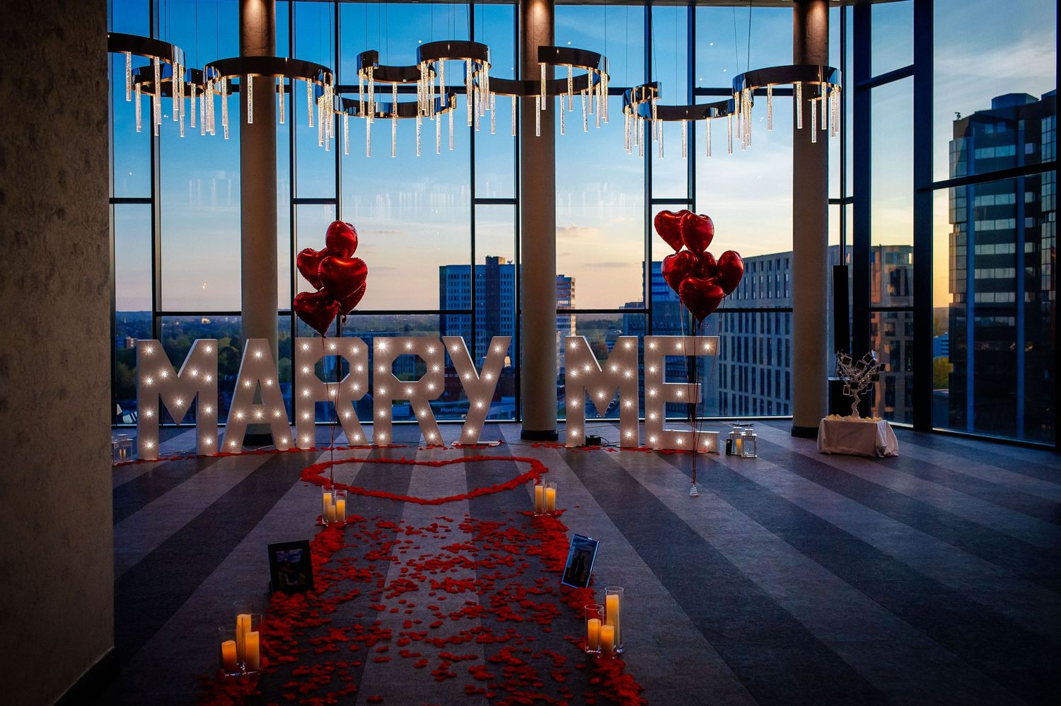 Romantic rooftop setting with red rose petals and candles creating an intimate atmosphere at sunset.