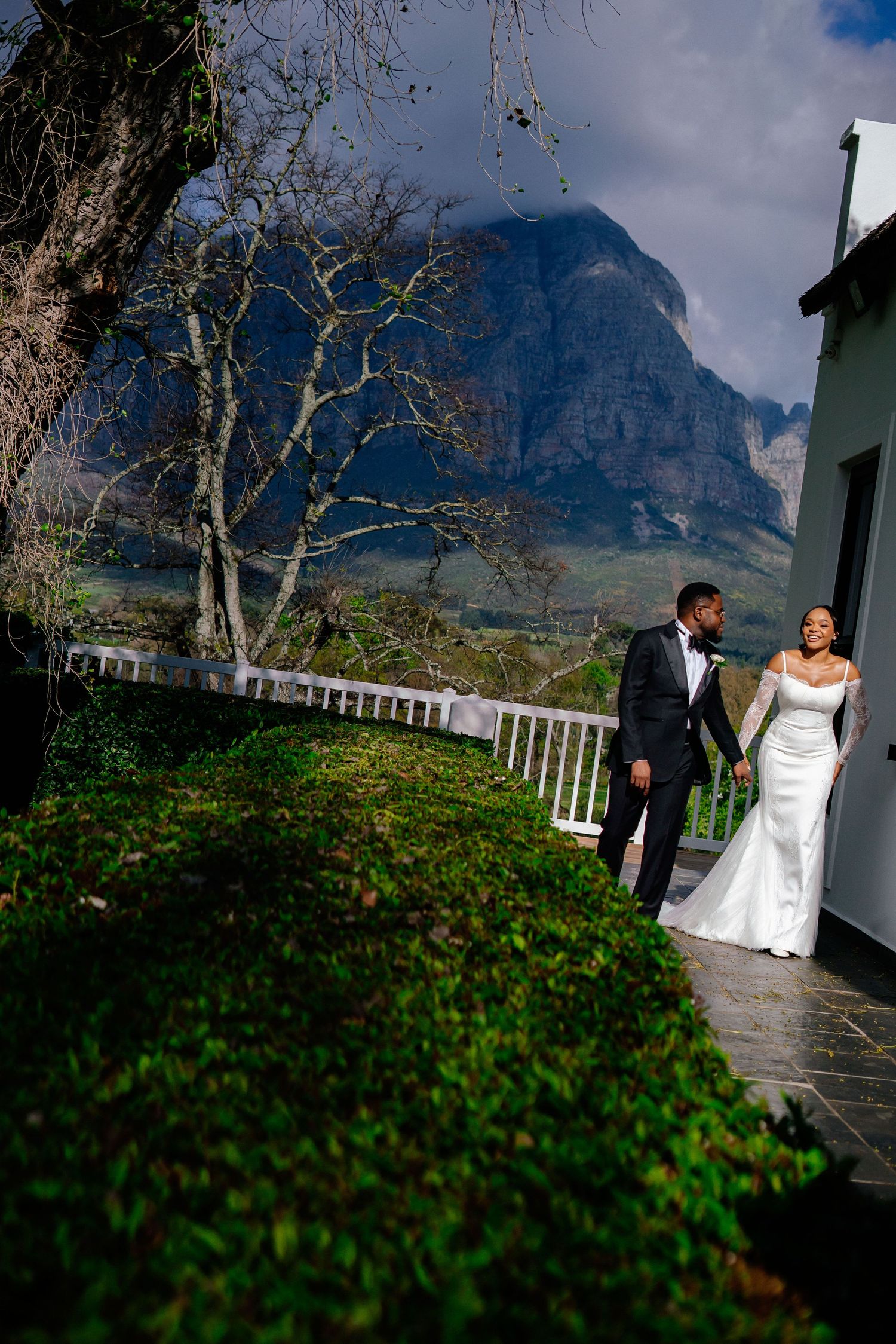 Wedding couple poses in garden with dramatic mountain backdrop in Cape Town.