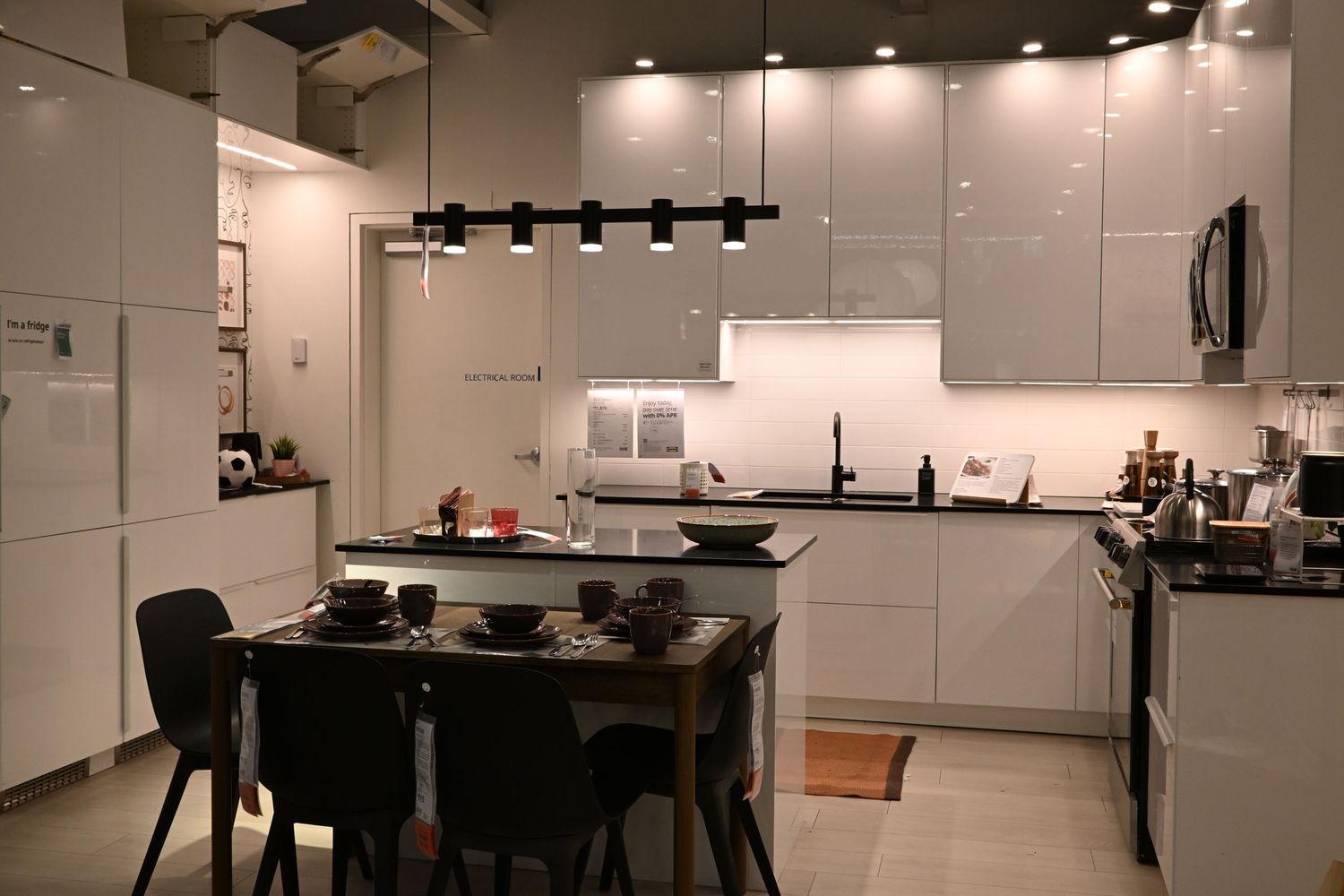 A modern kitchen interior featuring bright white cabinets, under-cabinet lighting, and an island dining area.