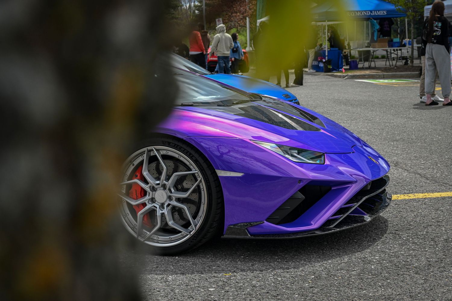 Close-up of the front wheel and fender of a metallic purple Lamborghini sports car parked outdoors.