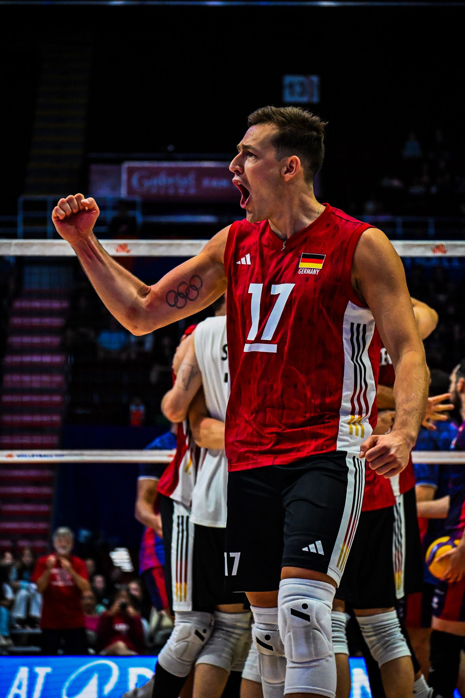 A volleyball player in a red jersey celebrating a point on an indoor court.