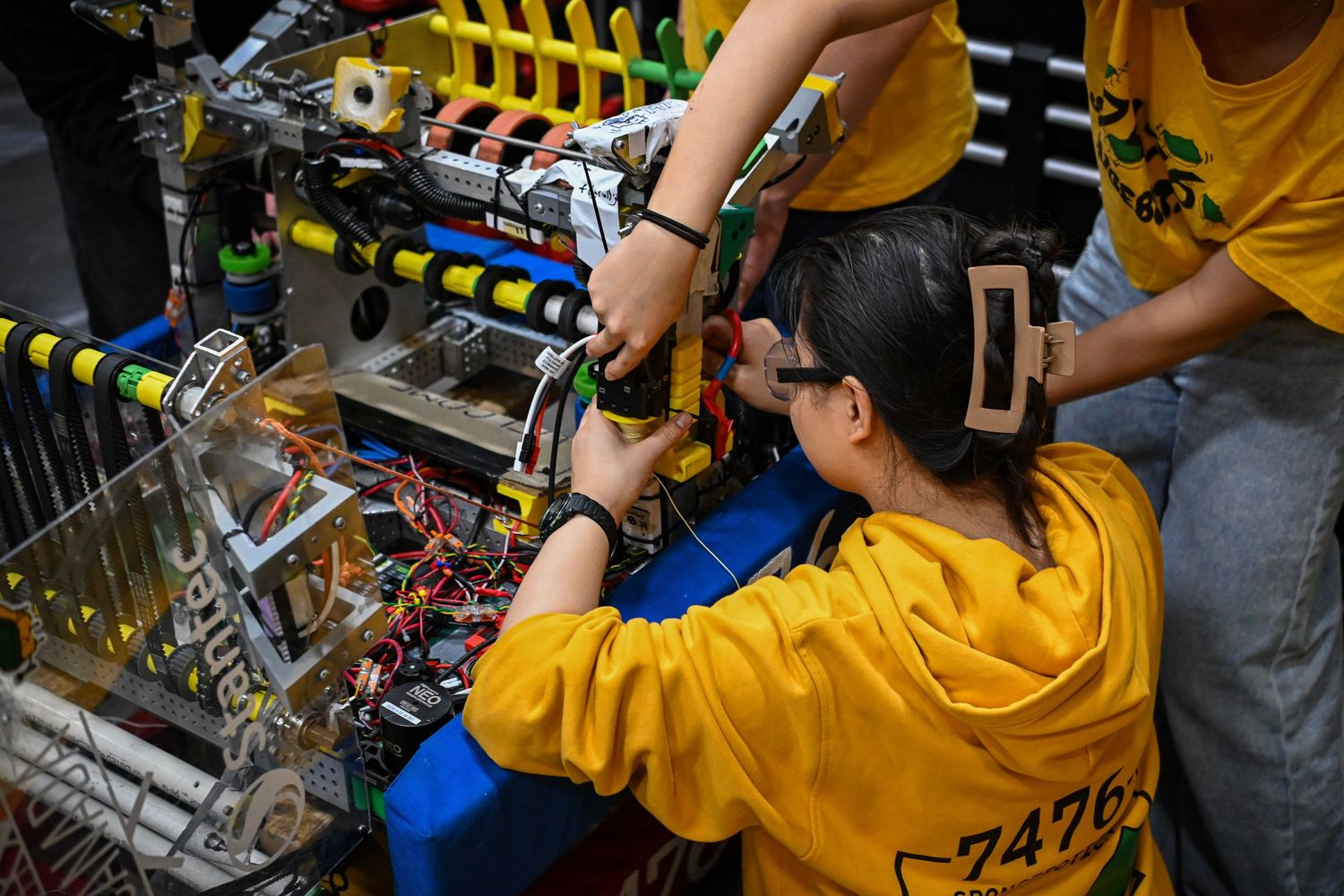 A close-up view of a student adjusting mechanical components on a complex competition robot.
