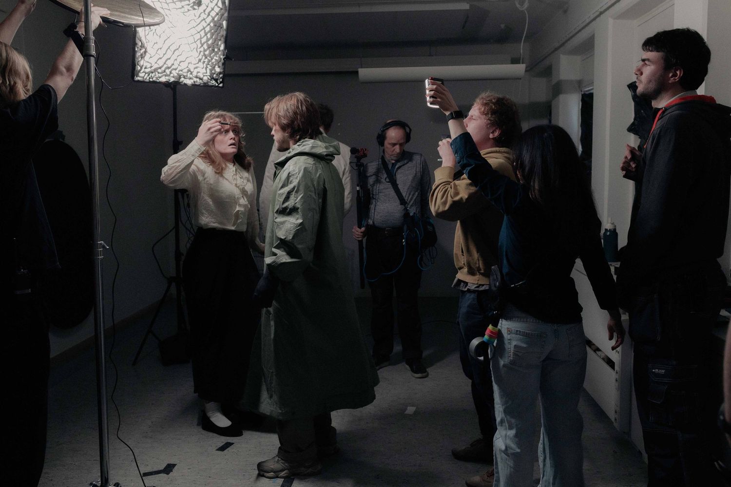 Behind-the-scenes film production crew working with lighting equipment in a dark studio space.