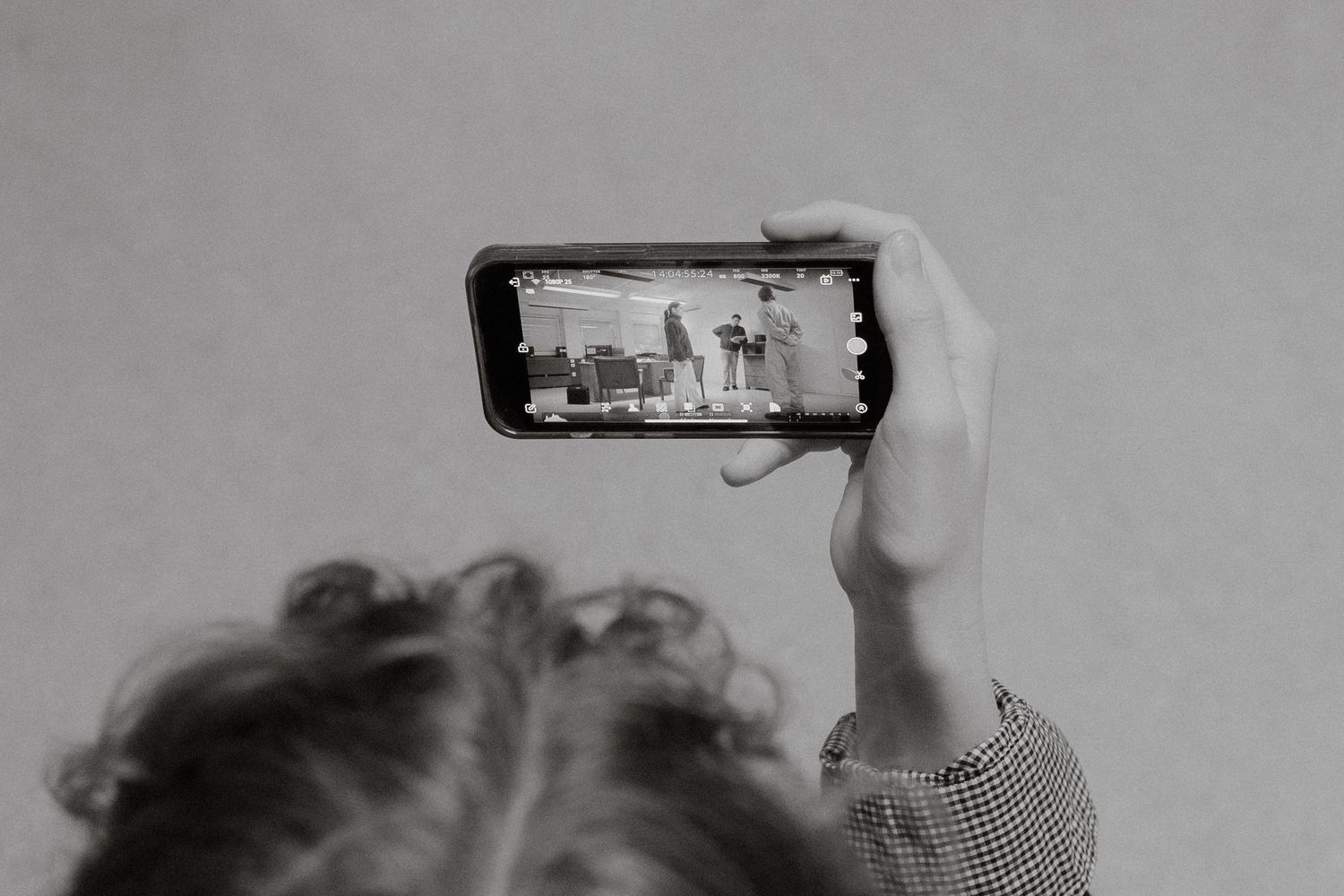Person holding a smartphone horizontally to photograph a cityscape in black and white.