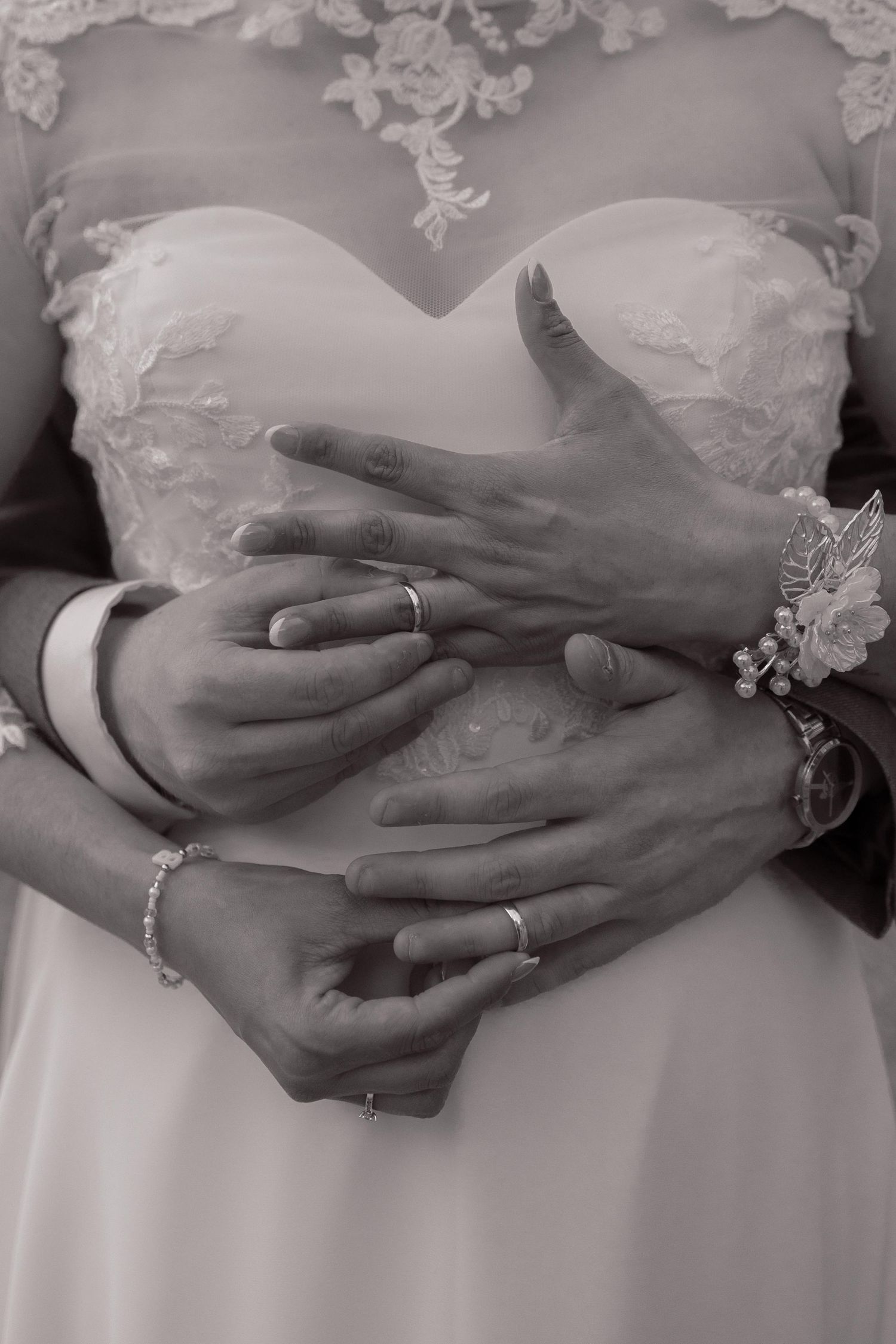 Close-up black and white photo of bride and groom hands intertwined showing wedding rings.