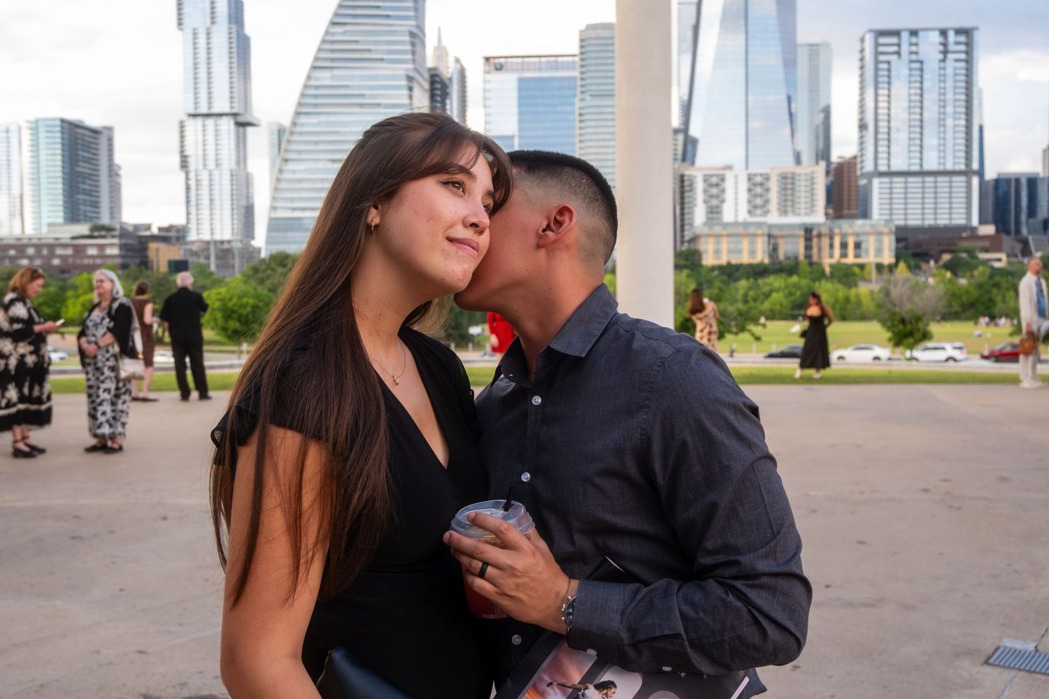 Young couple sharing a kiss in front of an Austin Texas city skyline on a sunny day.