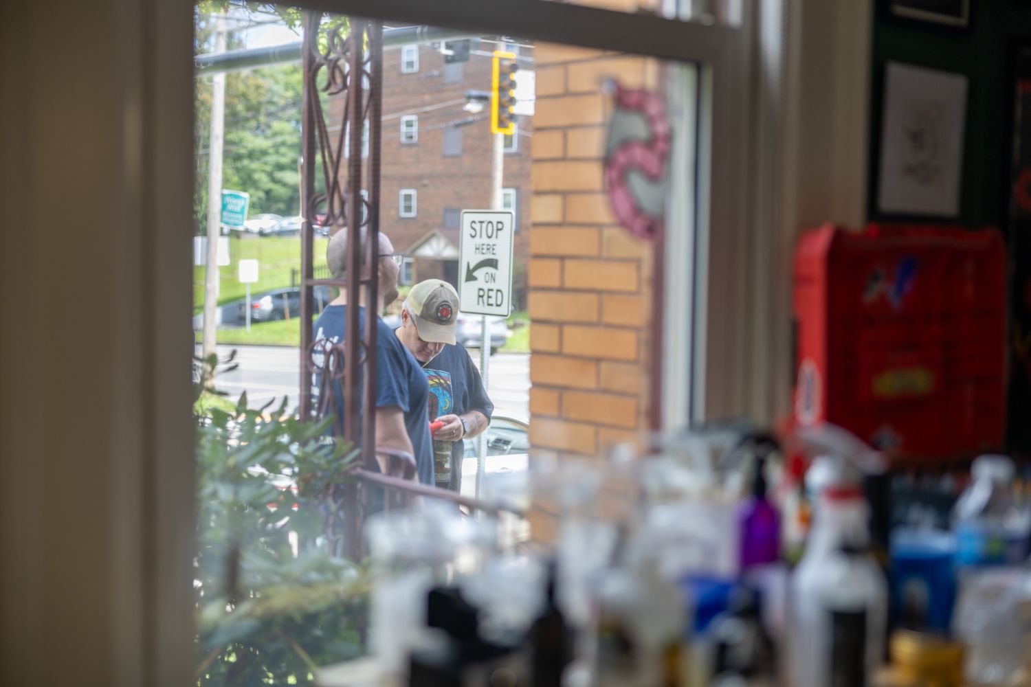 Person wearing mask viewed through salon window with beauty products on counter in foreground.