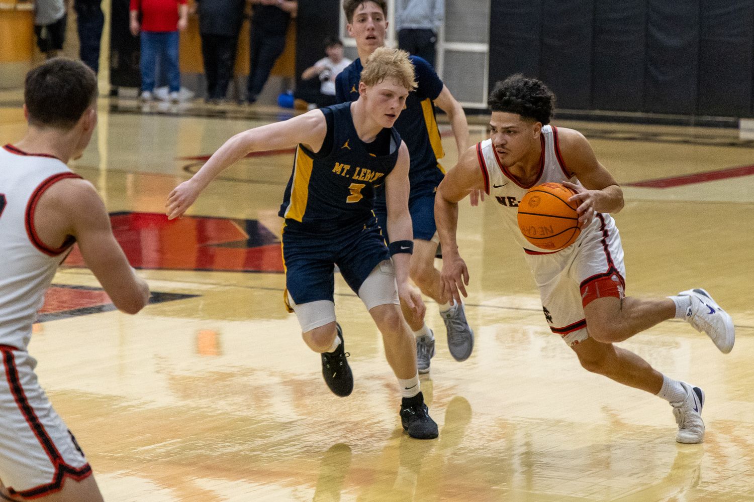 Ne-Ca-Hi player drives past a Mt. Lebanon defender during a competitive high school basketball game.