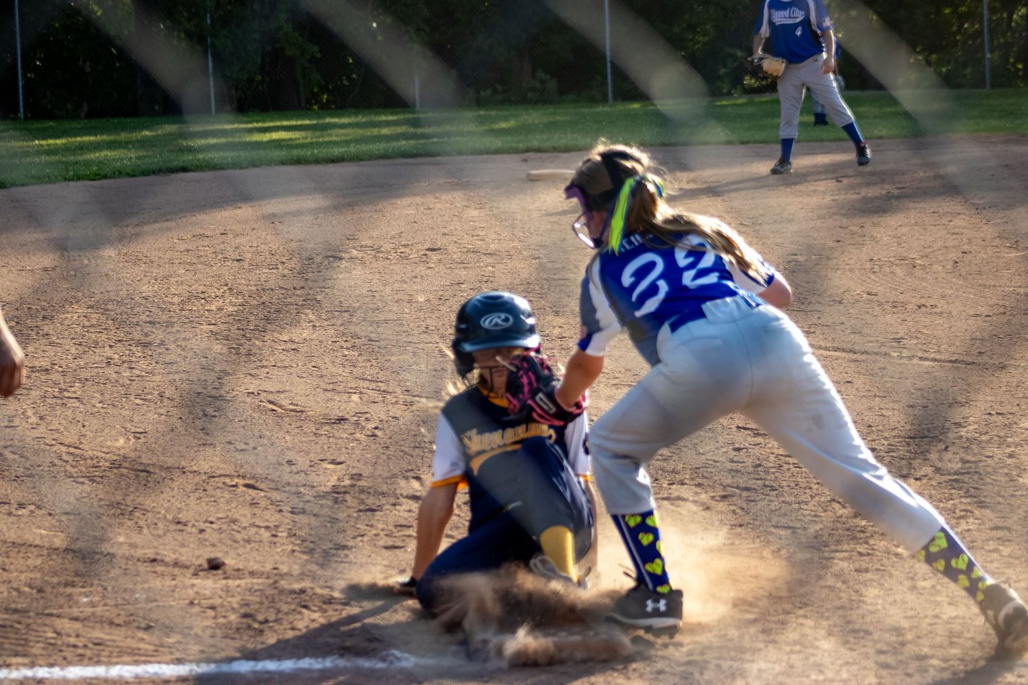 Softball catcher tags out sliding runner at home plate during an intense youth league game.