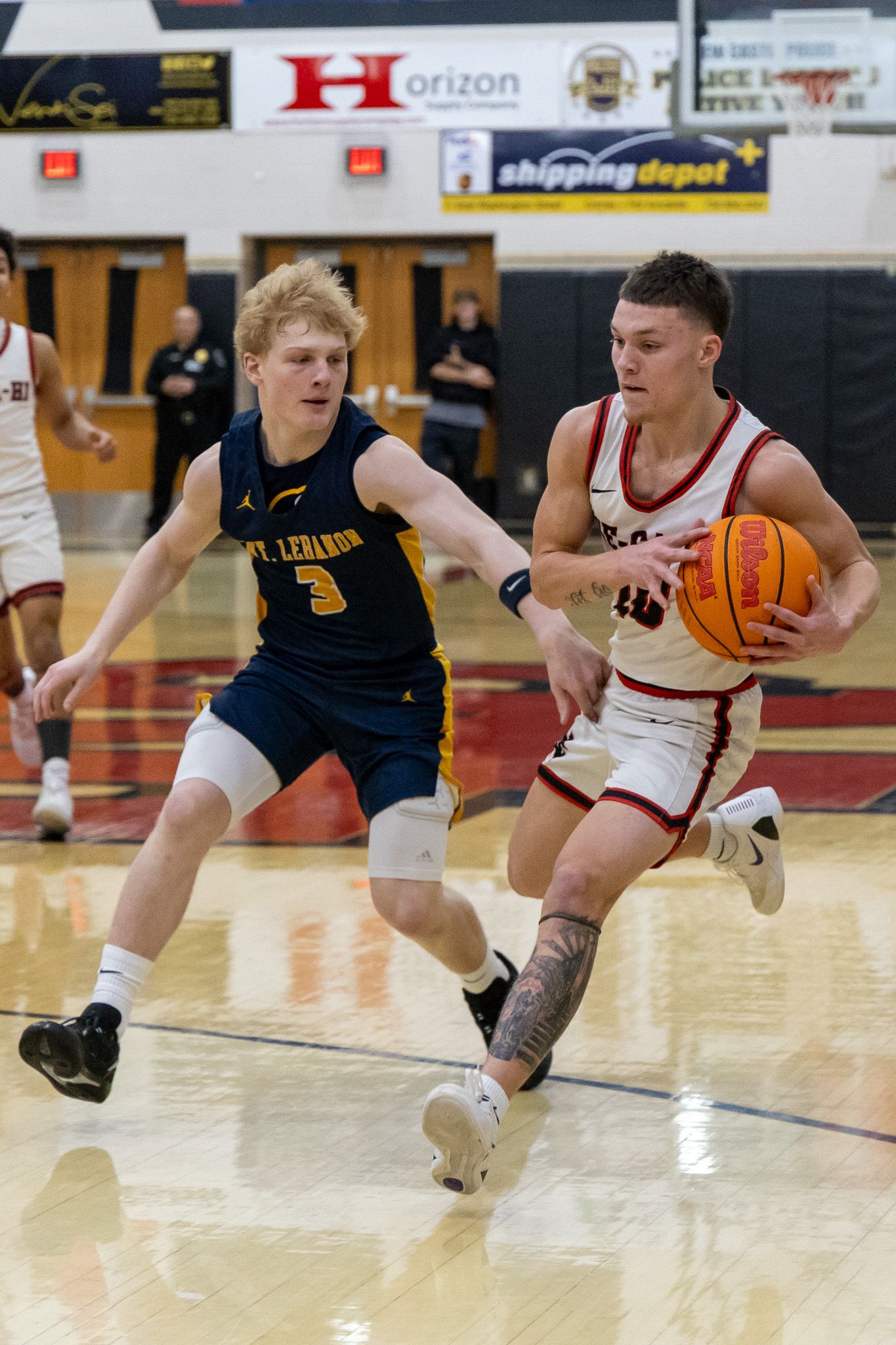 Mt. Lebanon #3 defends as a Ne-Ca-Hi player drives to the basket in a high school basketball game.