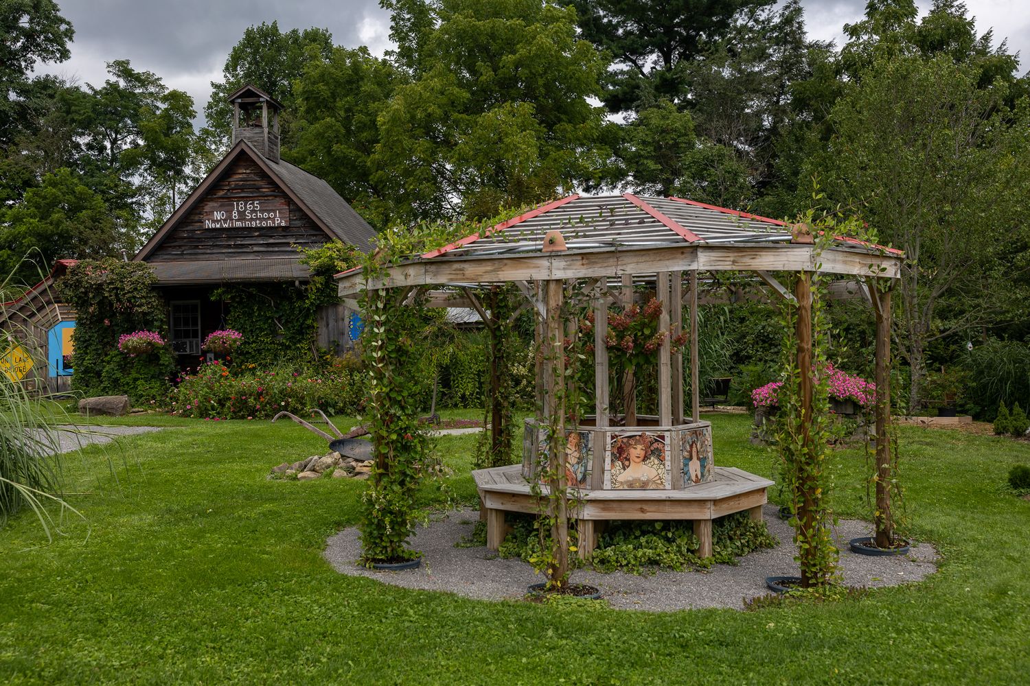 Rustic garden gazebo with climbing vines on a lush green lawn, with a charming cottage visible in the background.