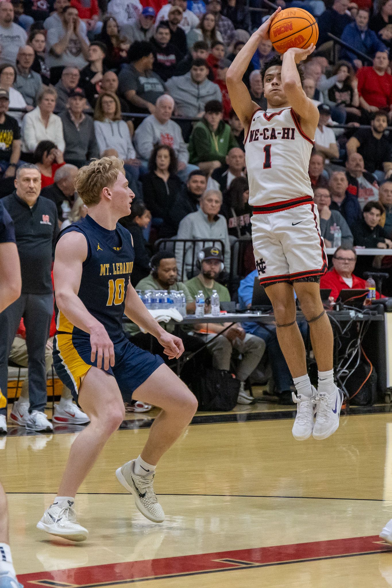 Player #1 in Ne-Ca-Hi uniform shoots a jump shot during a high school basketball game against Mt. Lebanon.