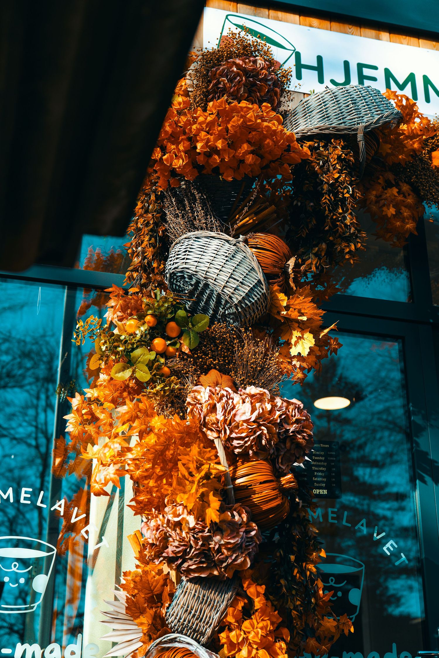 Vibrant autumn floral display with orange flowers, pumpkins, and wicker baskets decorating a storefront.