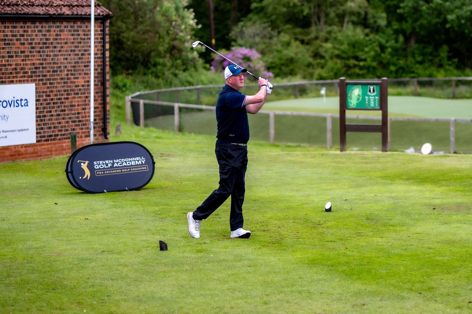 Male golfer follows through on a powerful tee shot at a PGA branded golf tournament.
