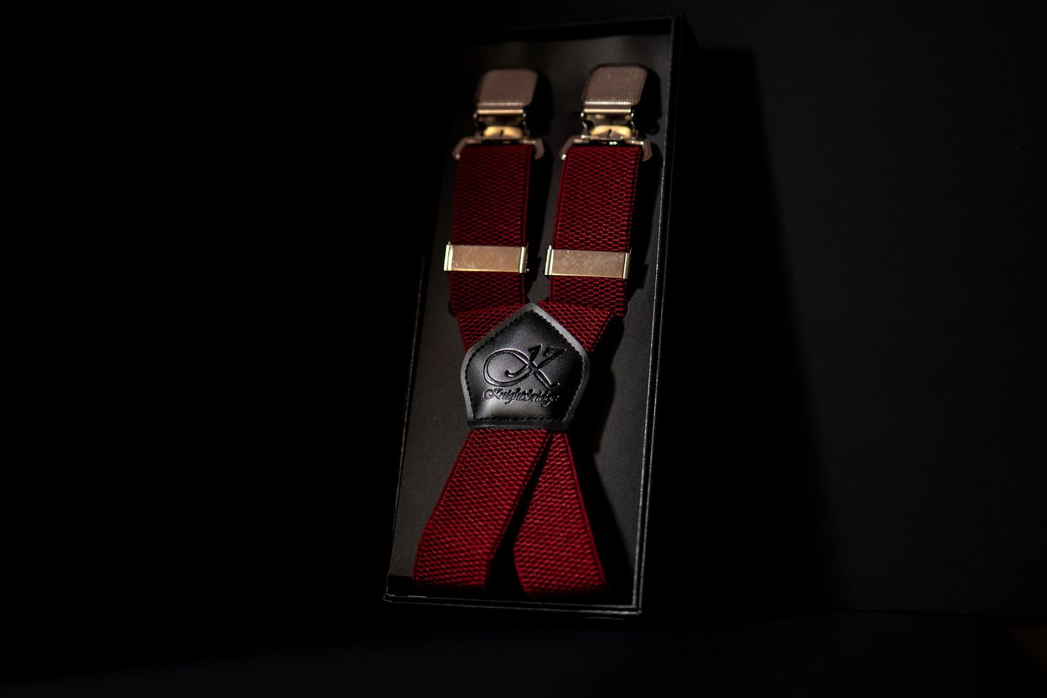 Burgundy red suspenders with leather Y-back detail displayed in black gift box.