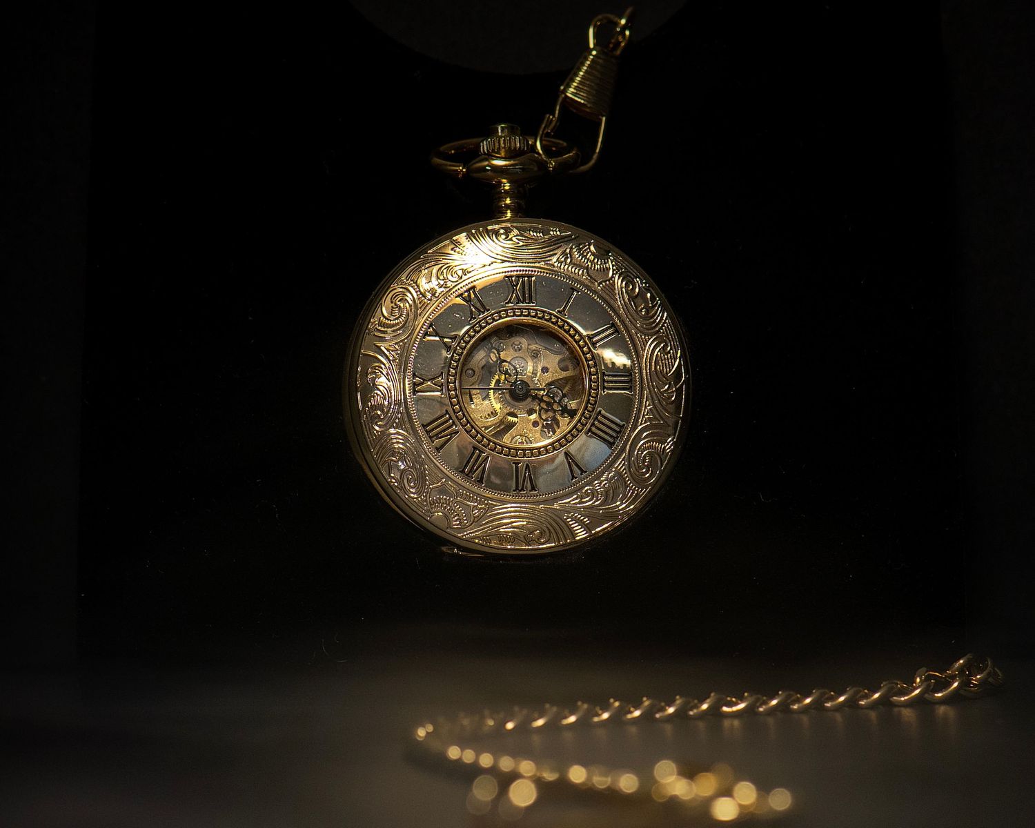 Elegant gold skeleton pocket watch with Roman numerals and intricate engravings hanging on a chain.