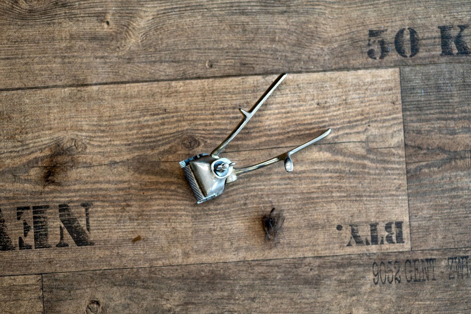 A vintage metal hair clip and pin rest on a rustic wooden surface with stenciled text.