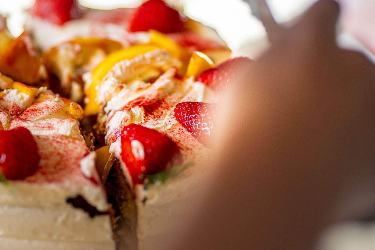 Close-up of decorated cake with strawberries, mango slices, and cream toppings.