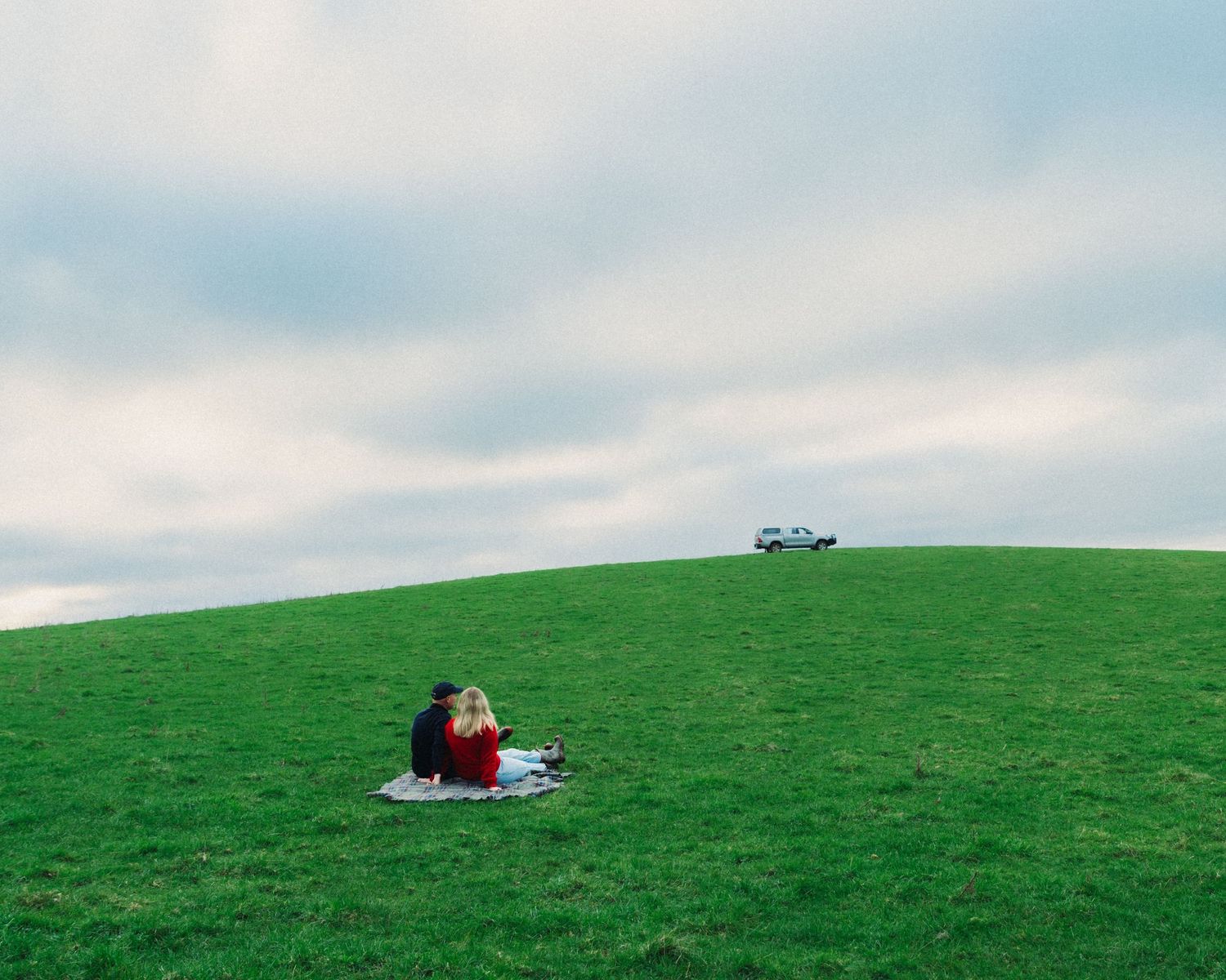 Couple on picnic blanket sitting in field
