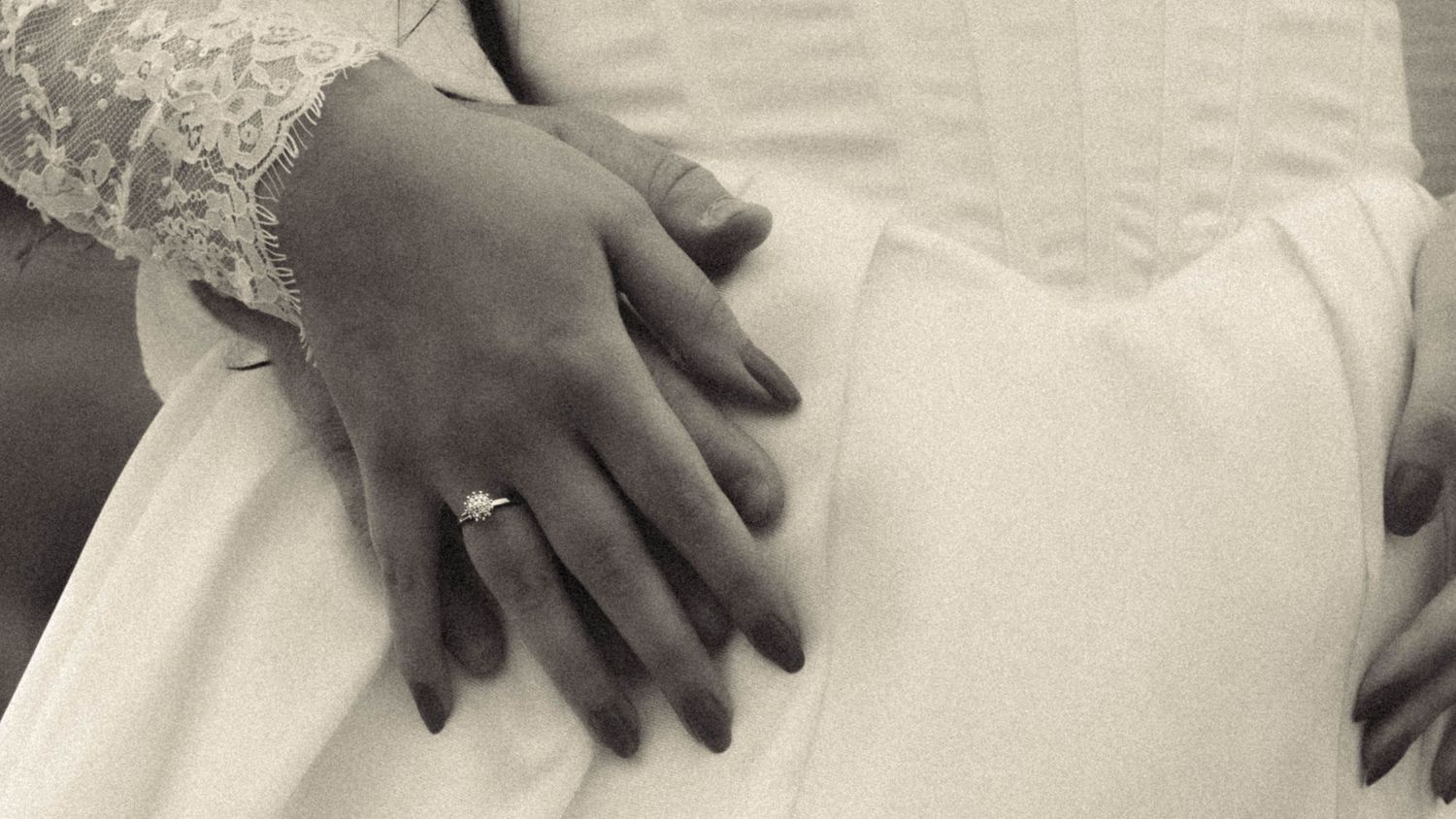 Close-up black and white photo of bride and groom hands with diamond engagement ring on wedding day. Located in Queenstown, New Zealand