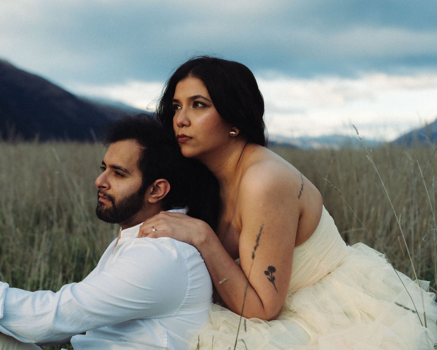 Wedding couple sitting in grassy field