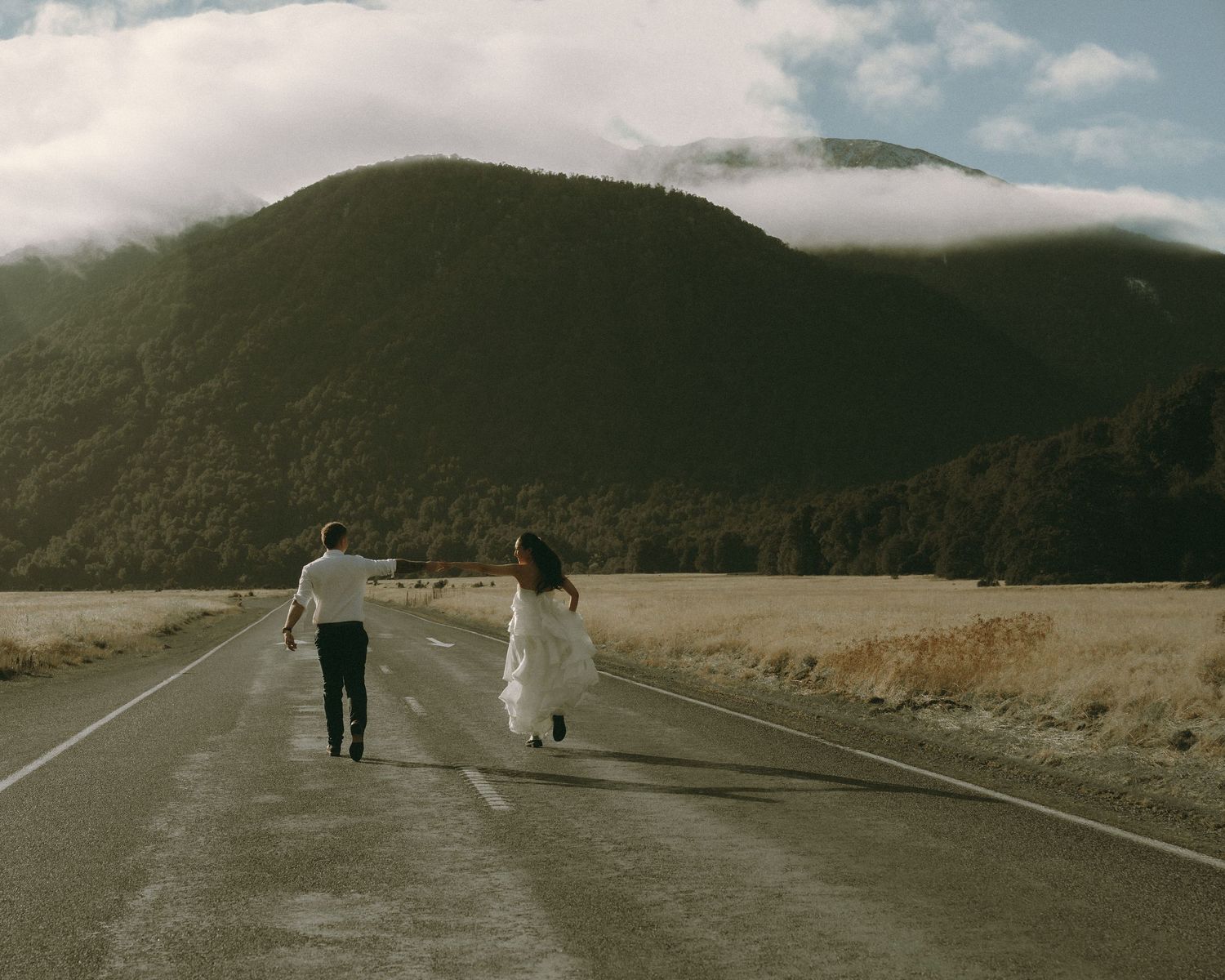 Wedding couple photograph. Walking down road with beautiful mountain landscape.