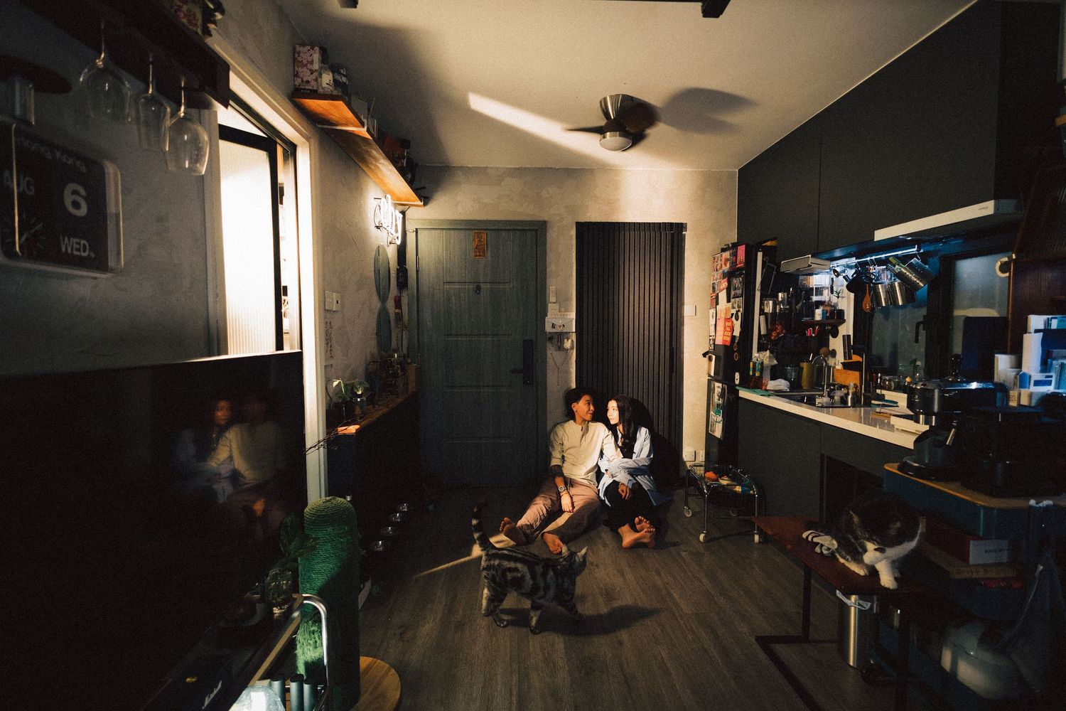 Couple relaxing together in a small dimly lit apartment with vintage decor.