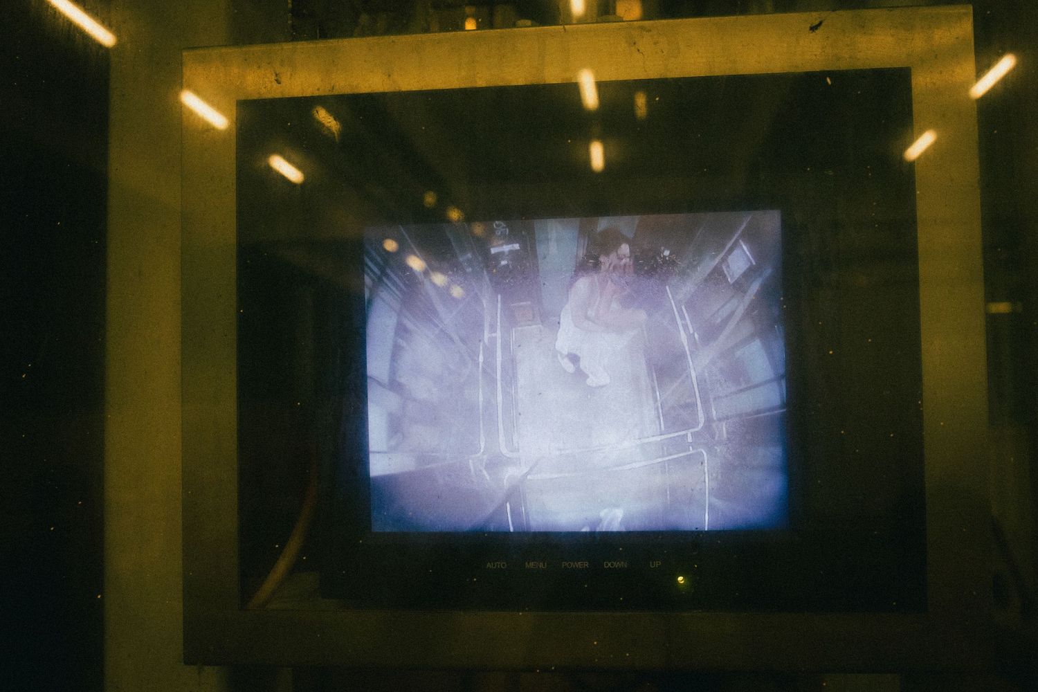 Grainy security monitor screen displaying a blurred interior space under yellow lighting.