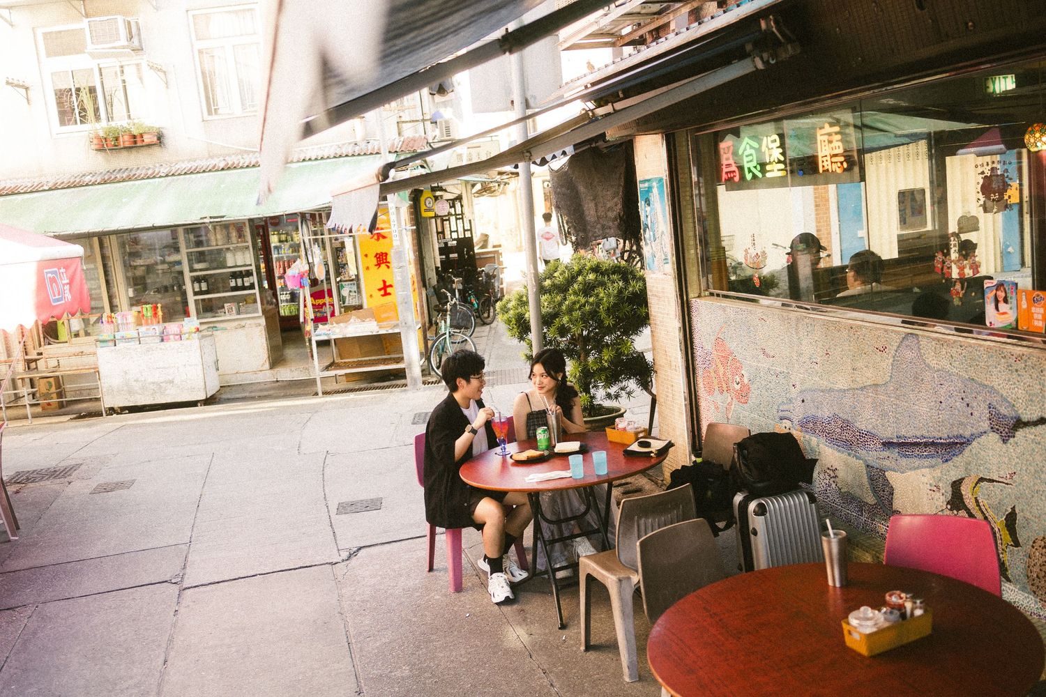 Couple sitting together at an outdoor street cafe surrounded by urban storefronts.