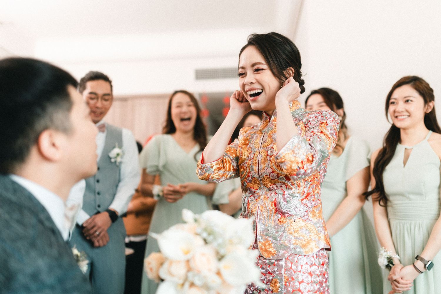 Joyful bride in colorful qipao reacts with delight upon seeing groom during traditional Chinese wedding tea ceremony.