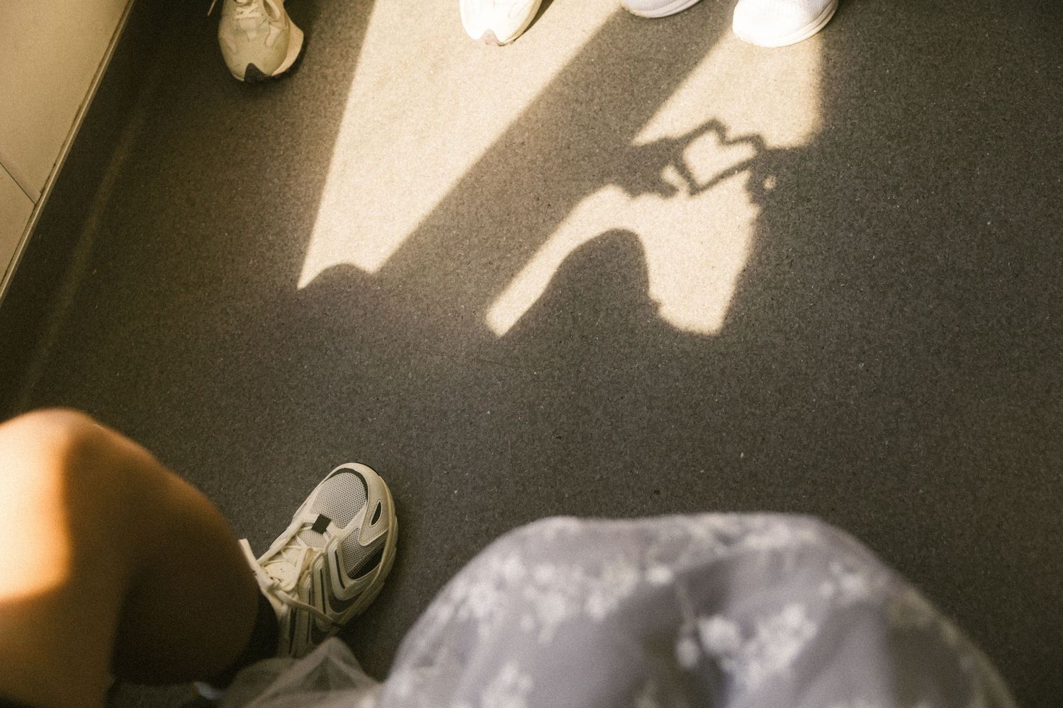 Shadow of a couple holding hands cast on the floor of a ferry with sneakers visible.