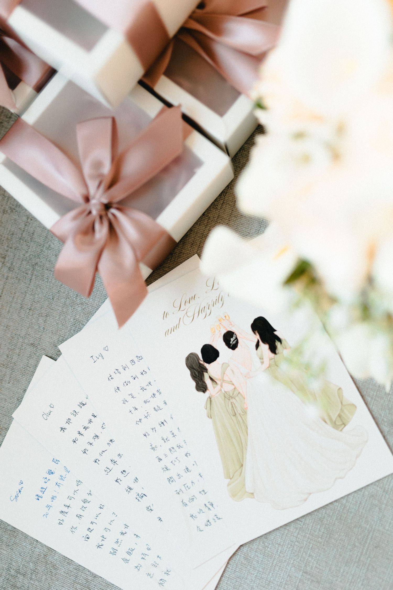 Chinese wedding stationery with illustrated bride and groom card, handwritten notes, and elegant gift boxes with pink satin bows.