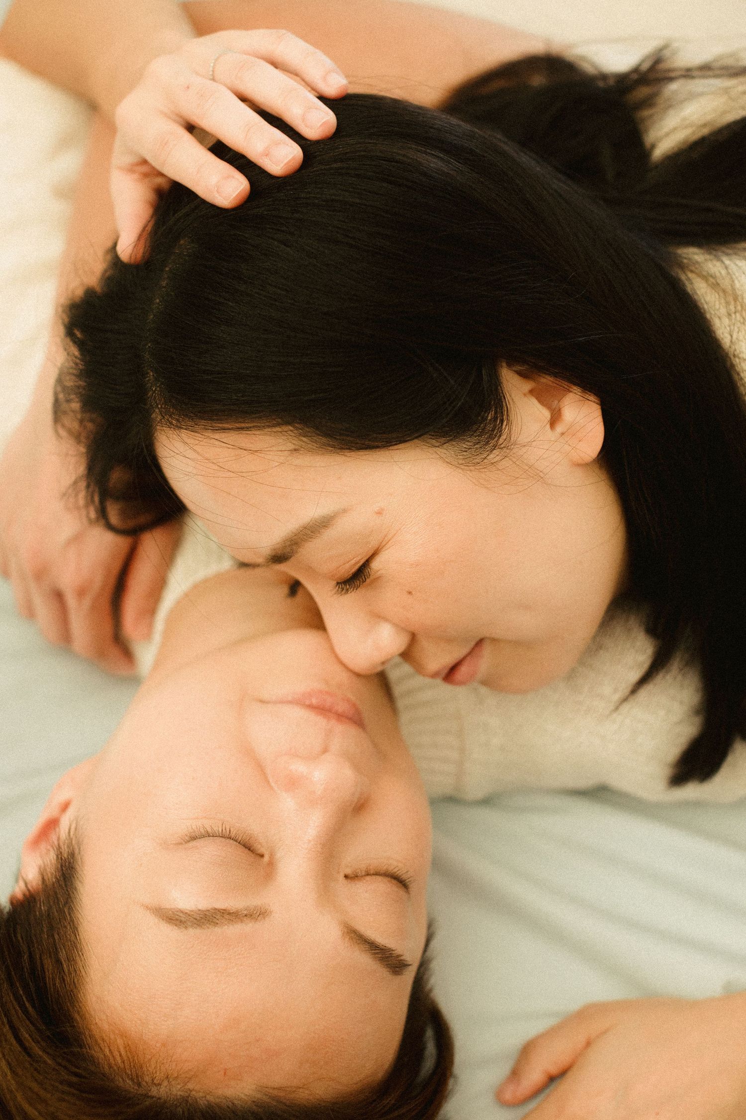 An intimate close-up of a couple with eyes closed sharing a tender moment lying together.