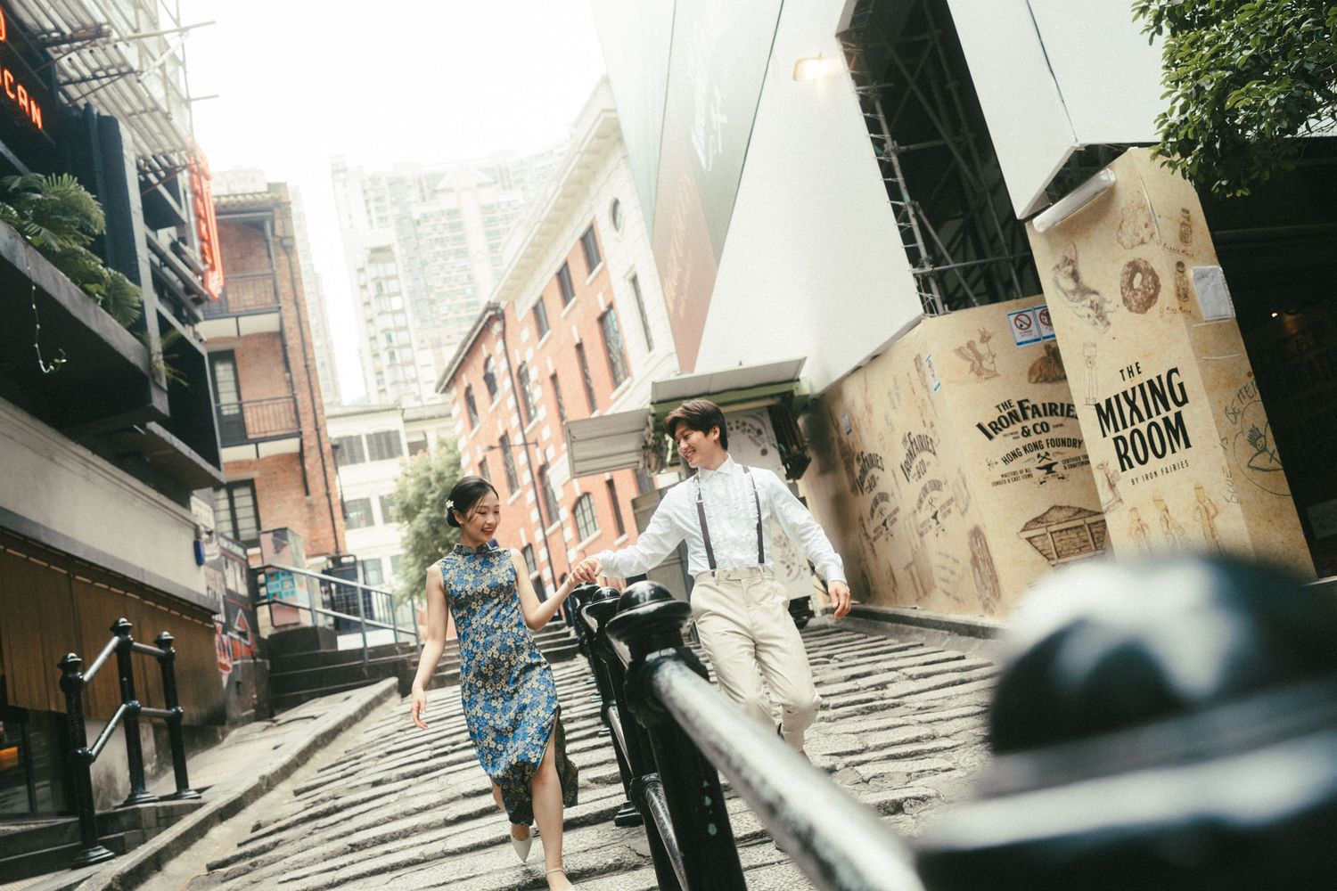 Couple in casual attire walking up urban steps in a vibrant city street setting.