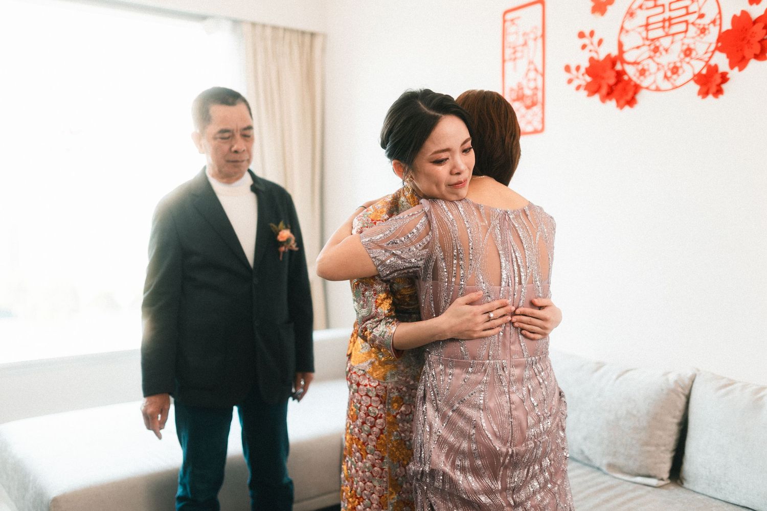 Emotional wedding morning moment as bride shares a heartfelt hug with her mother while father watches nearby.