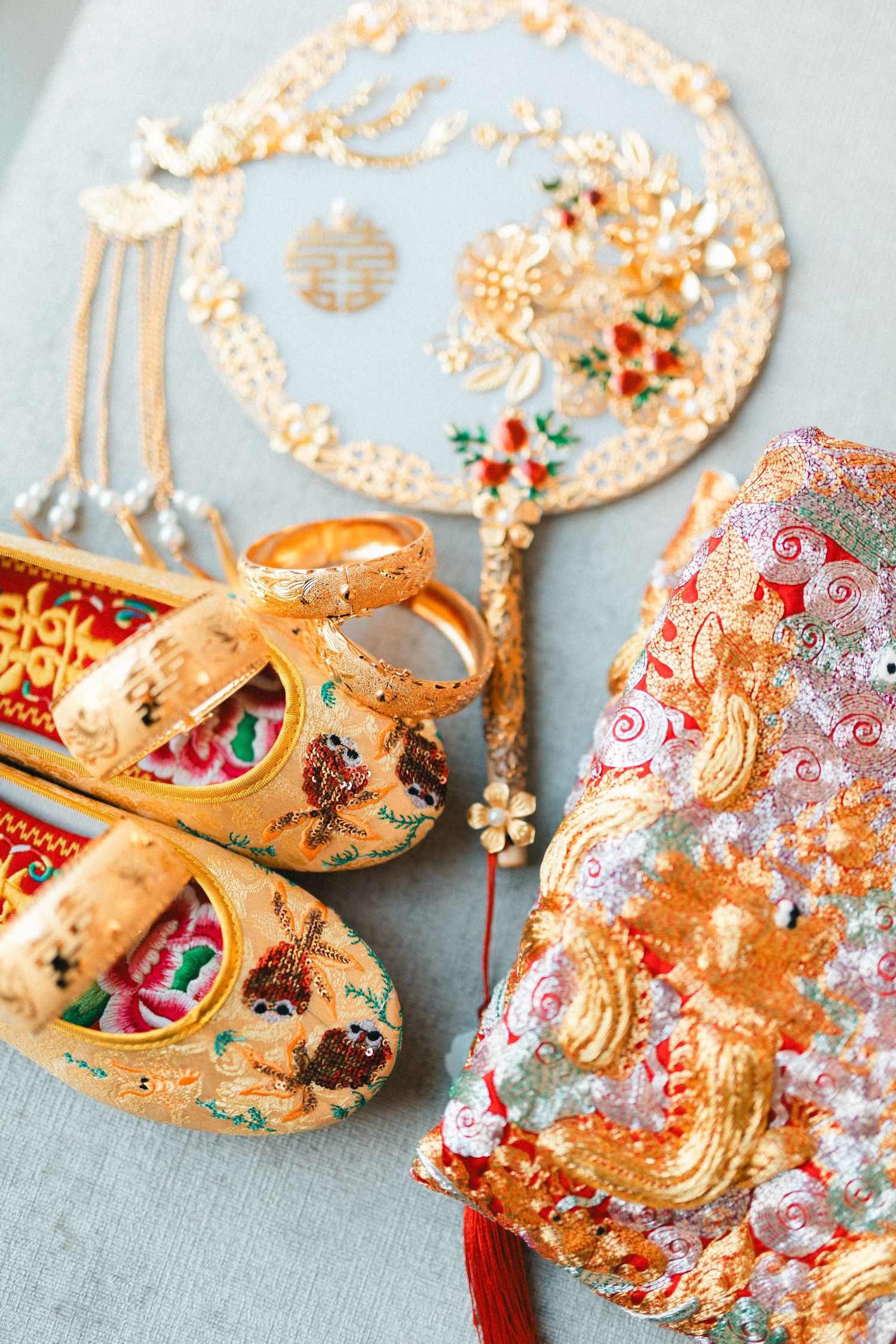 Traditional Chinese wedding accessories including embroidered gold shoes, decorative fan, and ornate red headpiece.