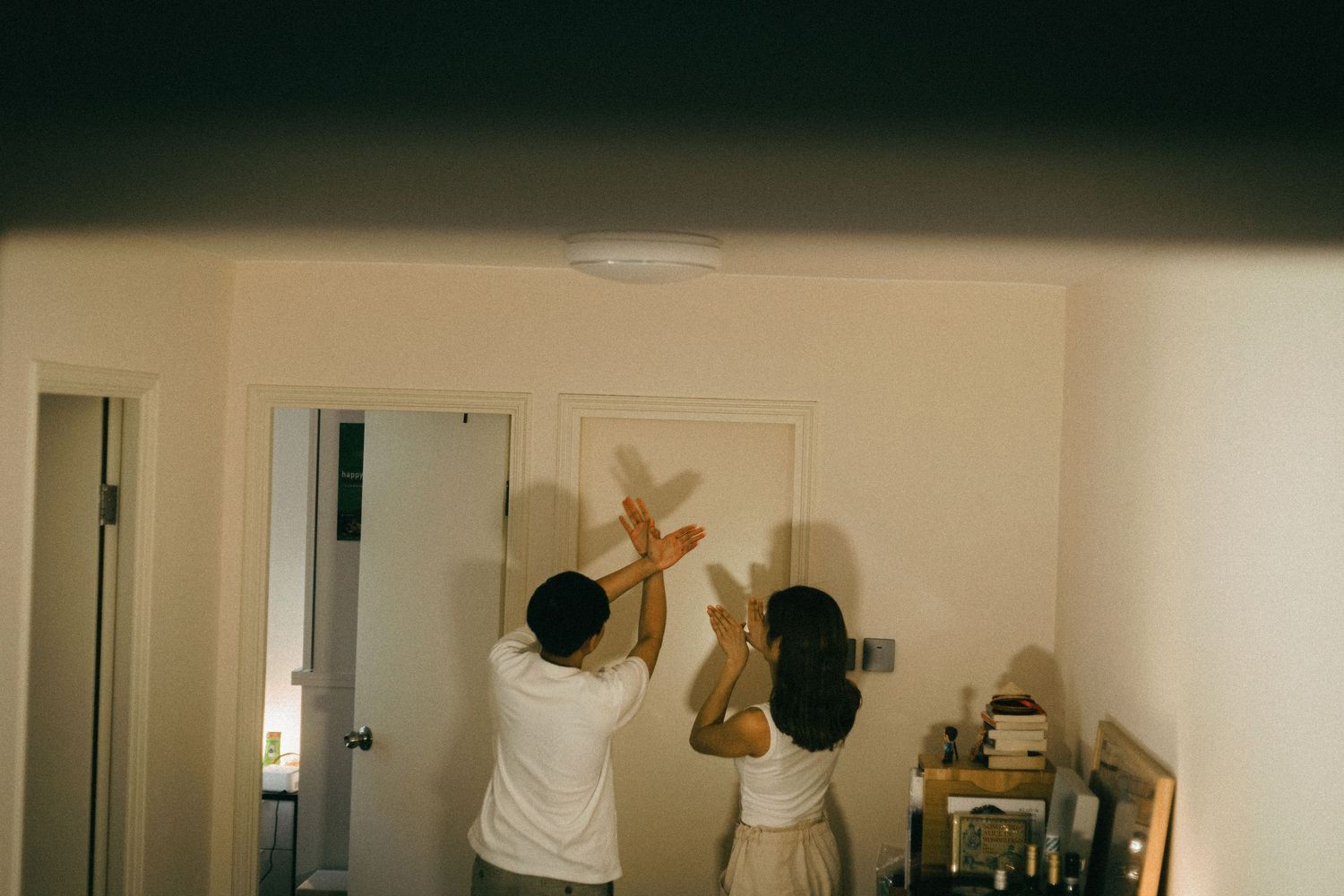 Two people hanging a decorative wooden star on a wall in a bright modern room.