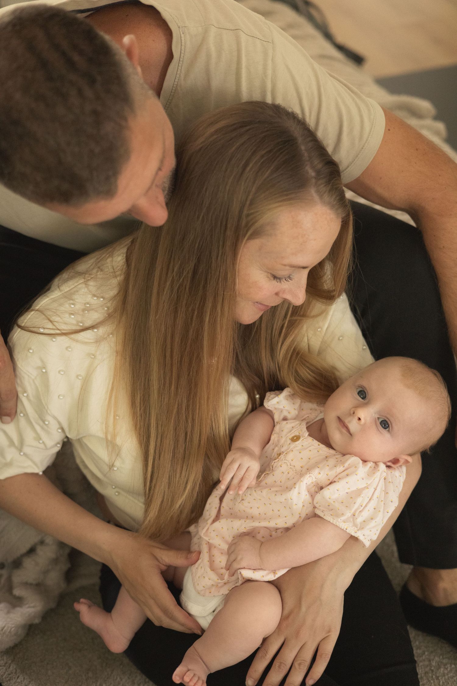 Young parents lovingly gazing at their newborn baby girl in a cozy home setting.