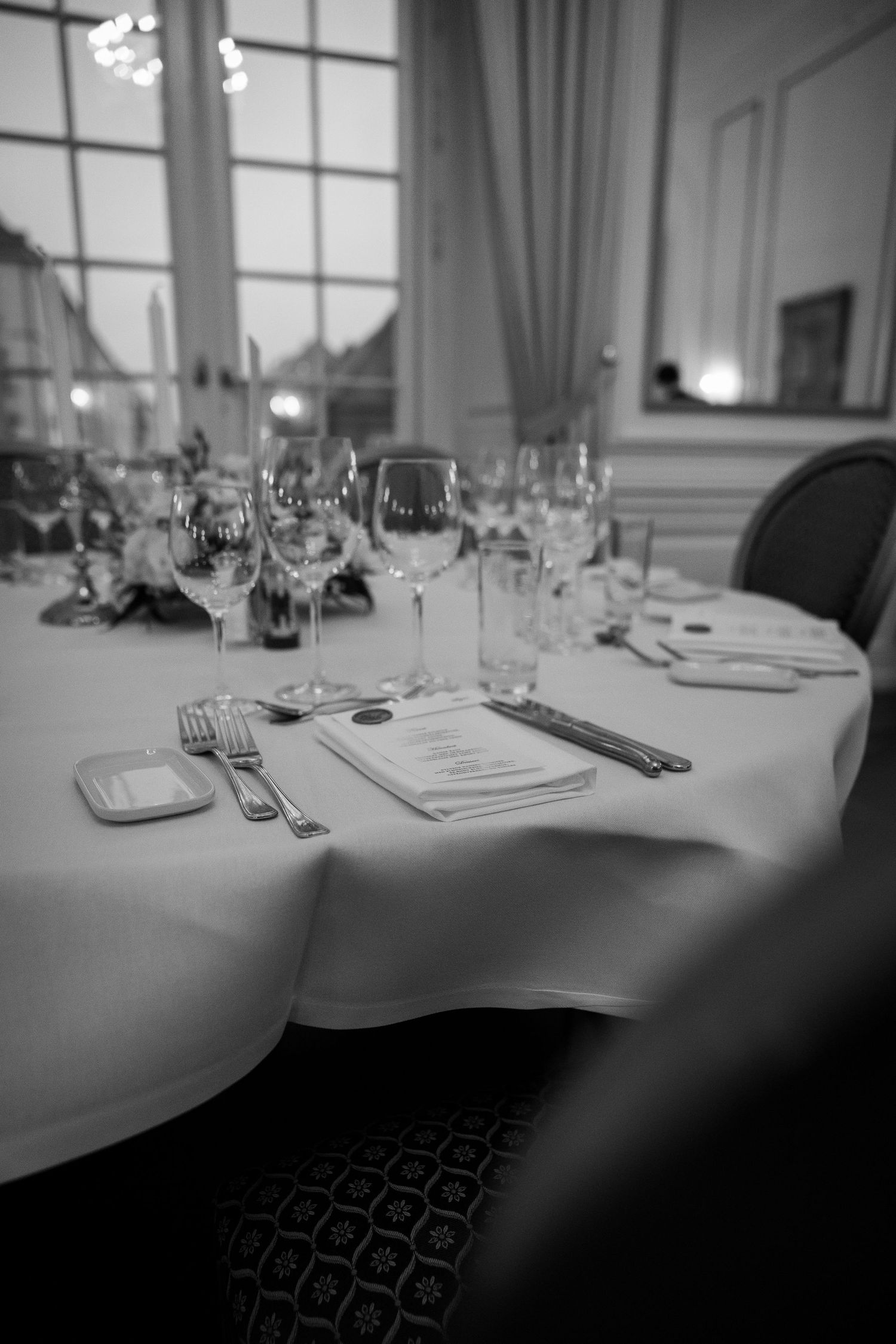 Elegant wedding reception table setting with crystal glassware, silverware, and menu cards on white linen.