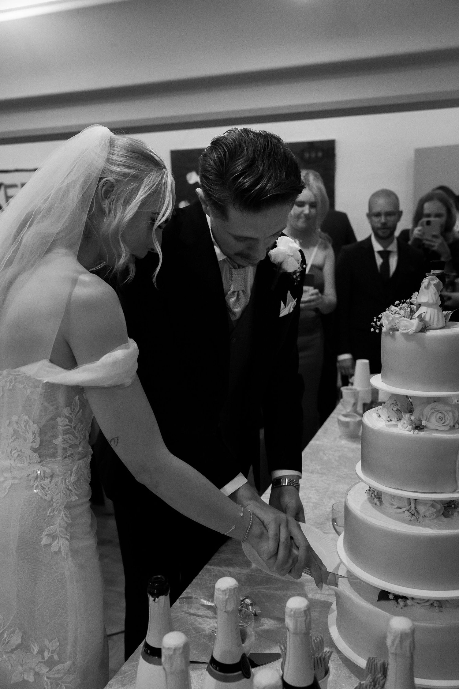 Bride and groom cutting tiered wedding cake in black and white photo.