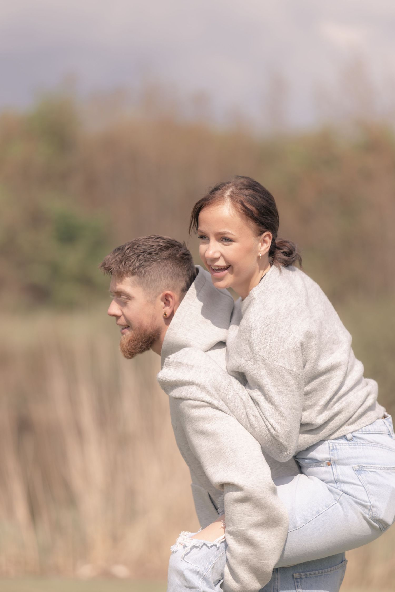 Smiling woman enjoying a piggyback ride on mans back in an outdoor natural setting.