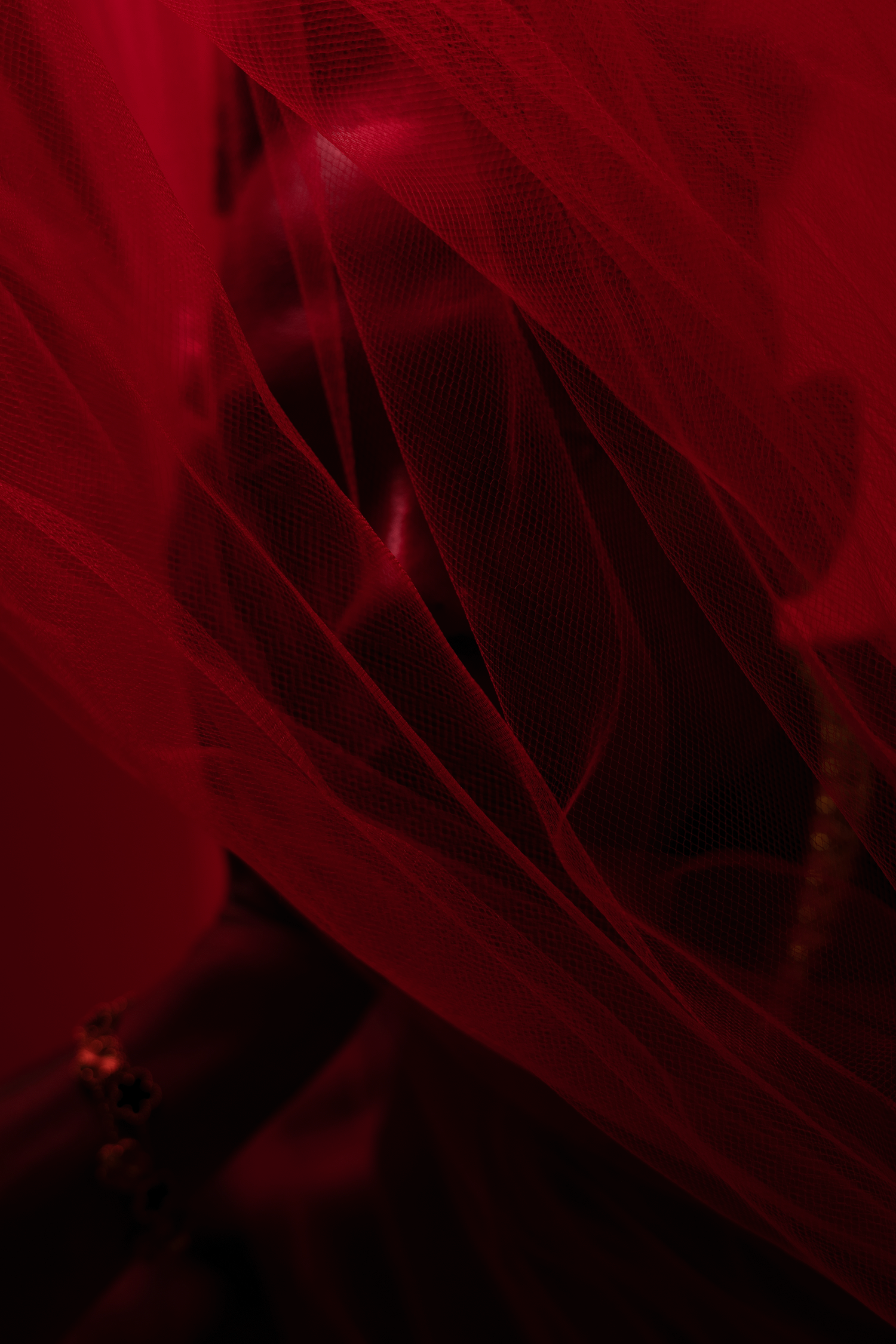Abstract close-up of deep red tulle fabric with dramatic lighting and rich texture.