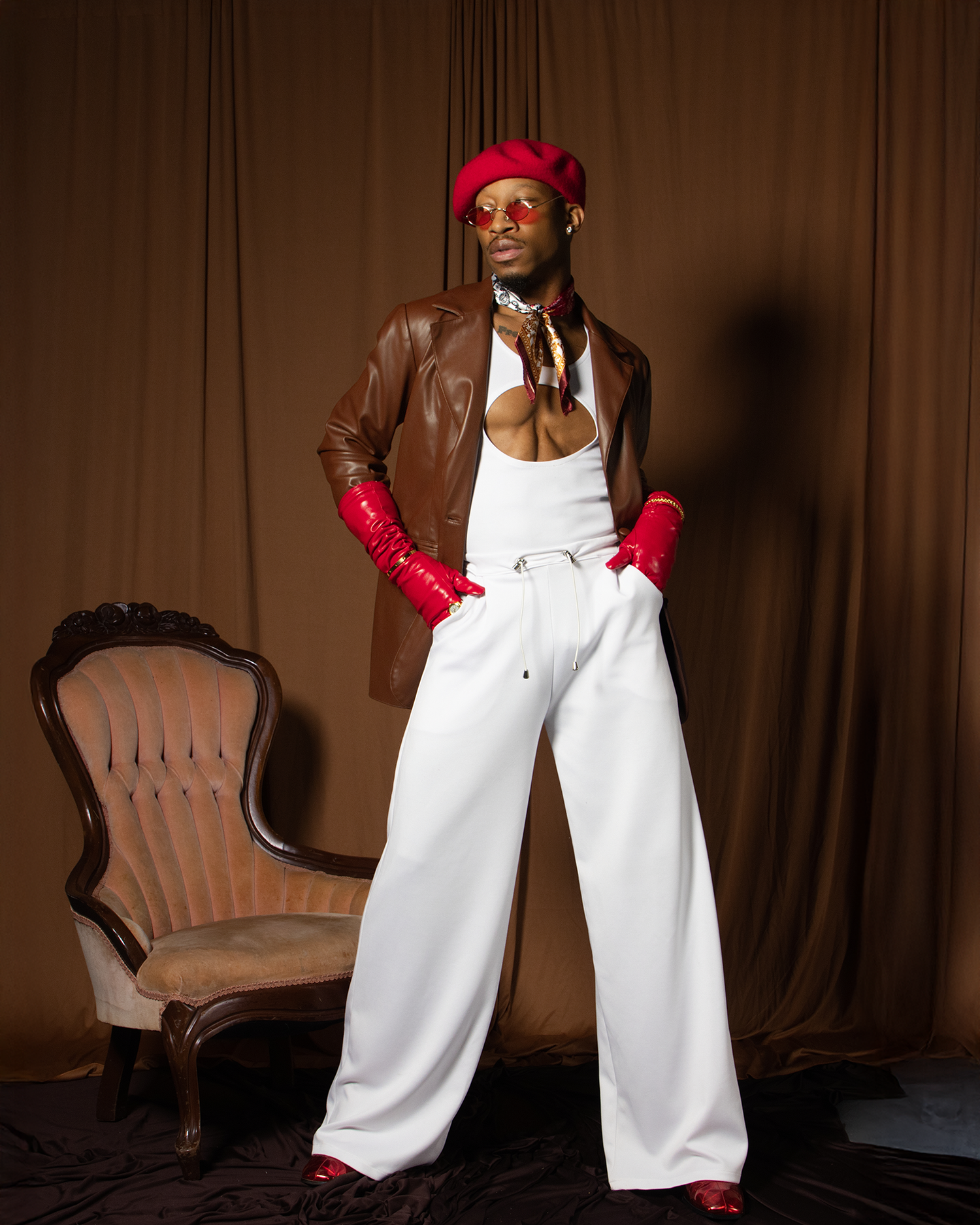 A fashion model in white wide-leg pants, red beret, leather jacket, and red gloves poses confidently.