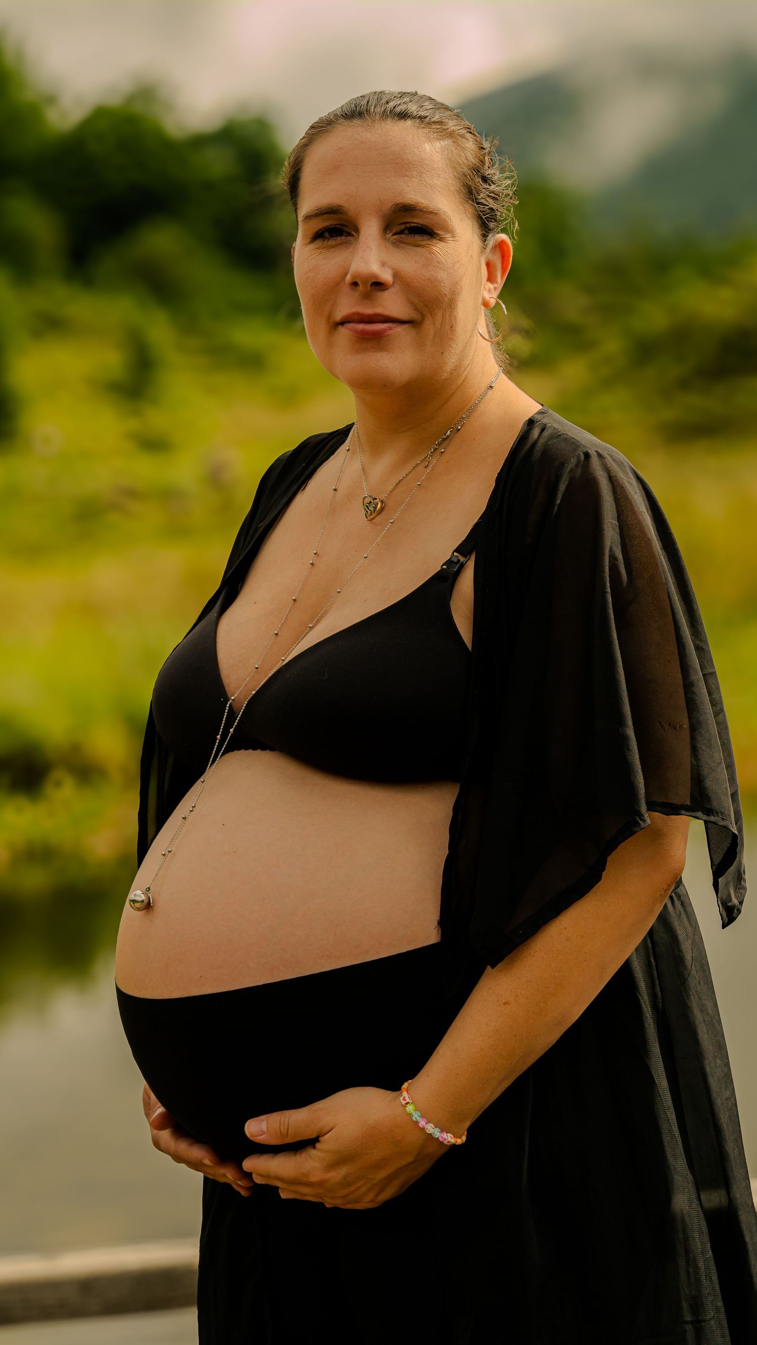 Future maman tenant son ventre lors d'une séance photo grossesse en lumière naturelle en Ariège.