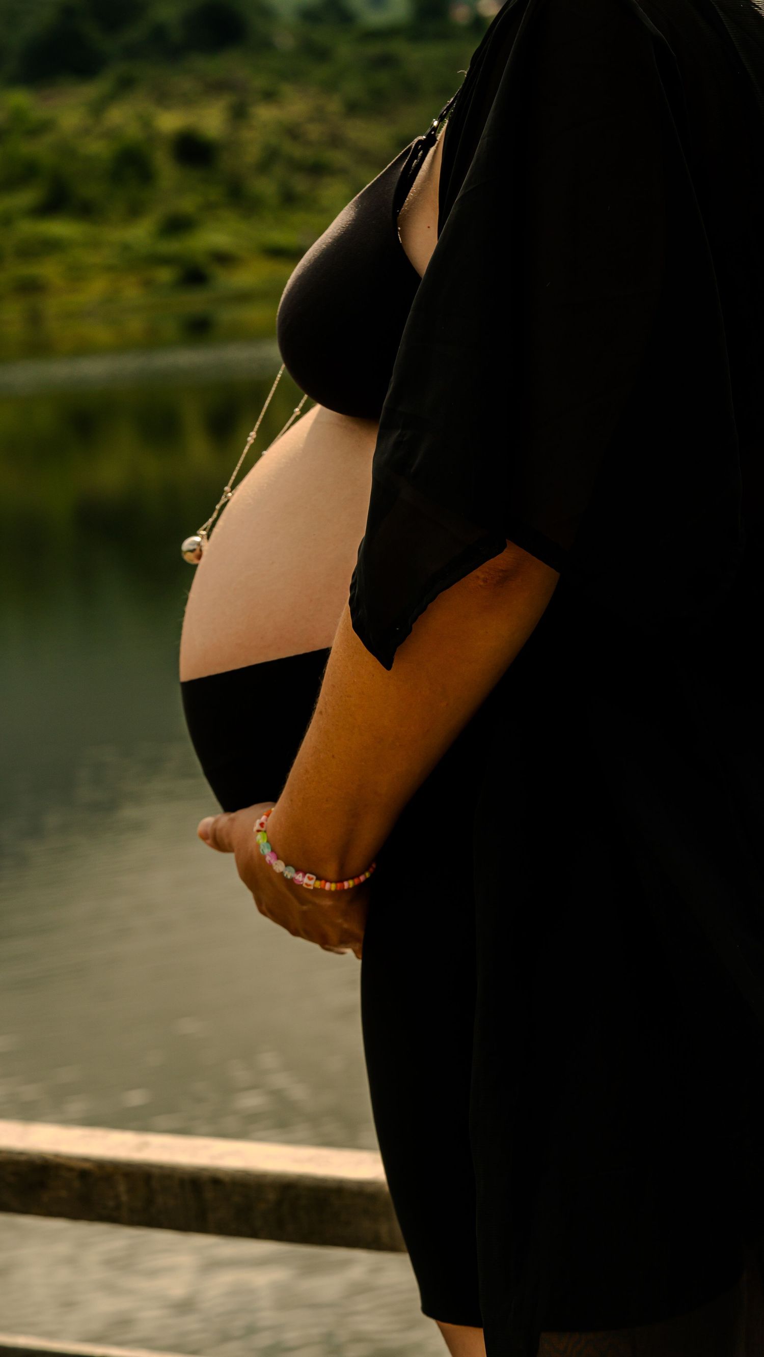 Future maman tenant son ventre lors d'une séance photo grossesse en lumière naturelle en Ariège.
