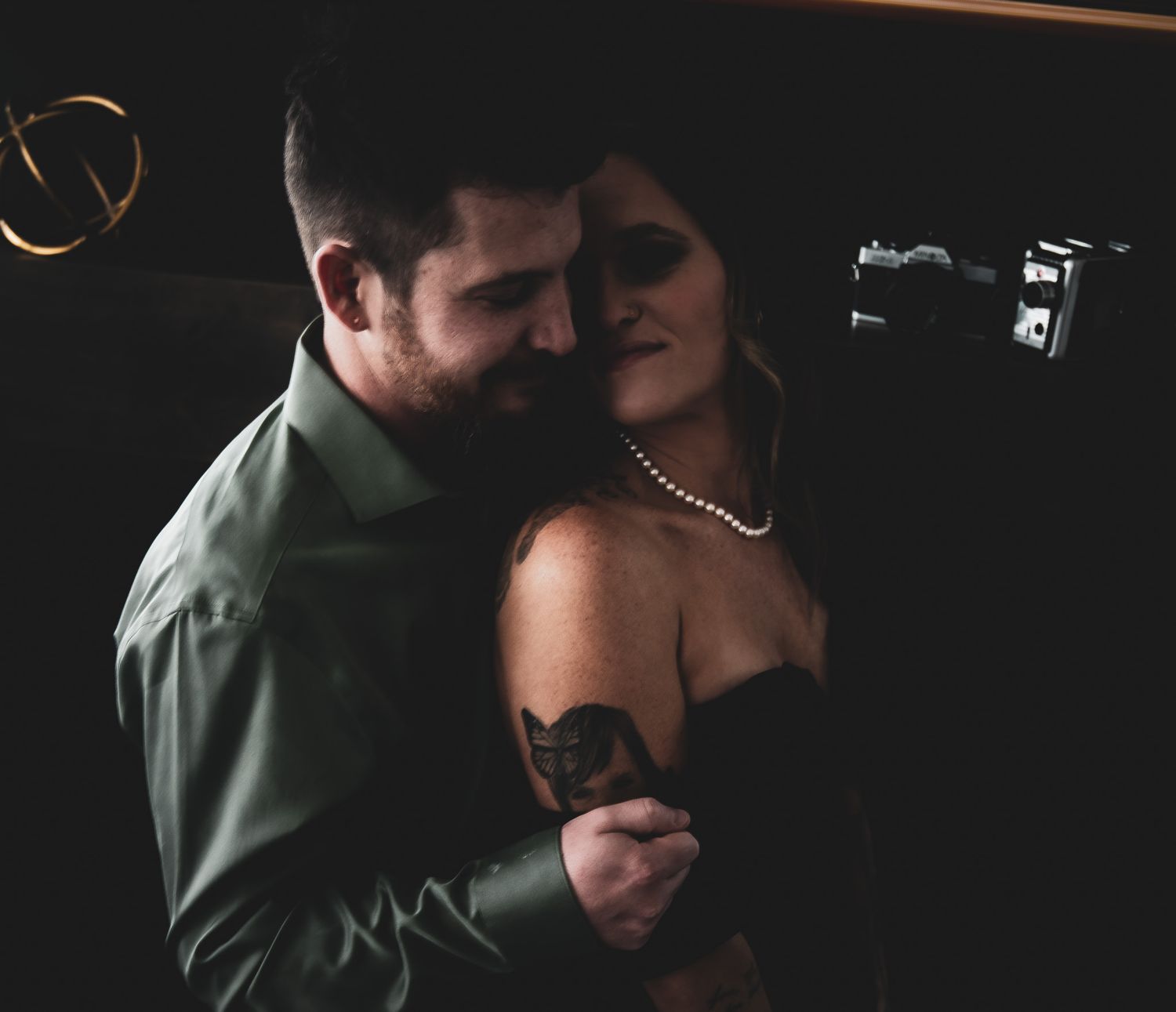 Couple in an intimate embrace in a dark, moody setting with soft lighting.