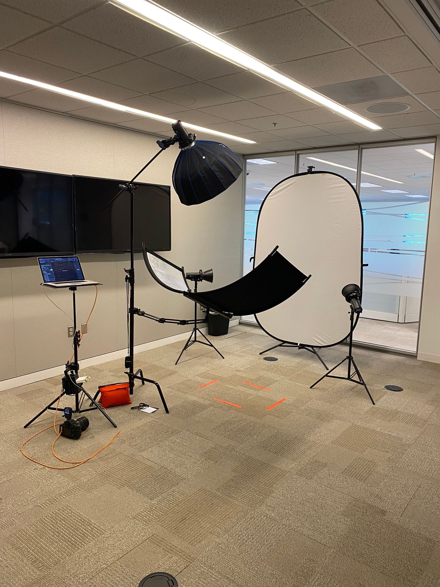 Professional photography studio setup with lighting equipment and backdrop in modern office space.