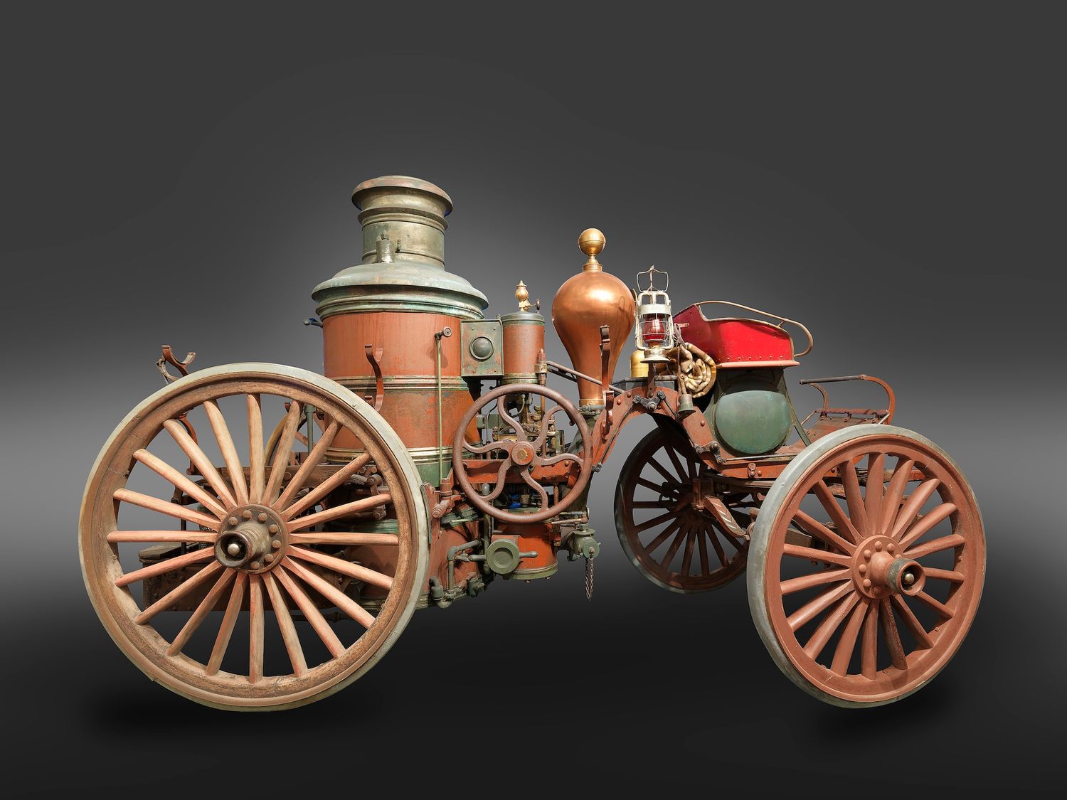 Antique steam-powered vehicle with large wooden spoke wheels and copper boiler on gray background.